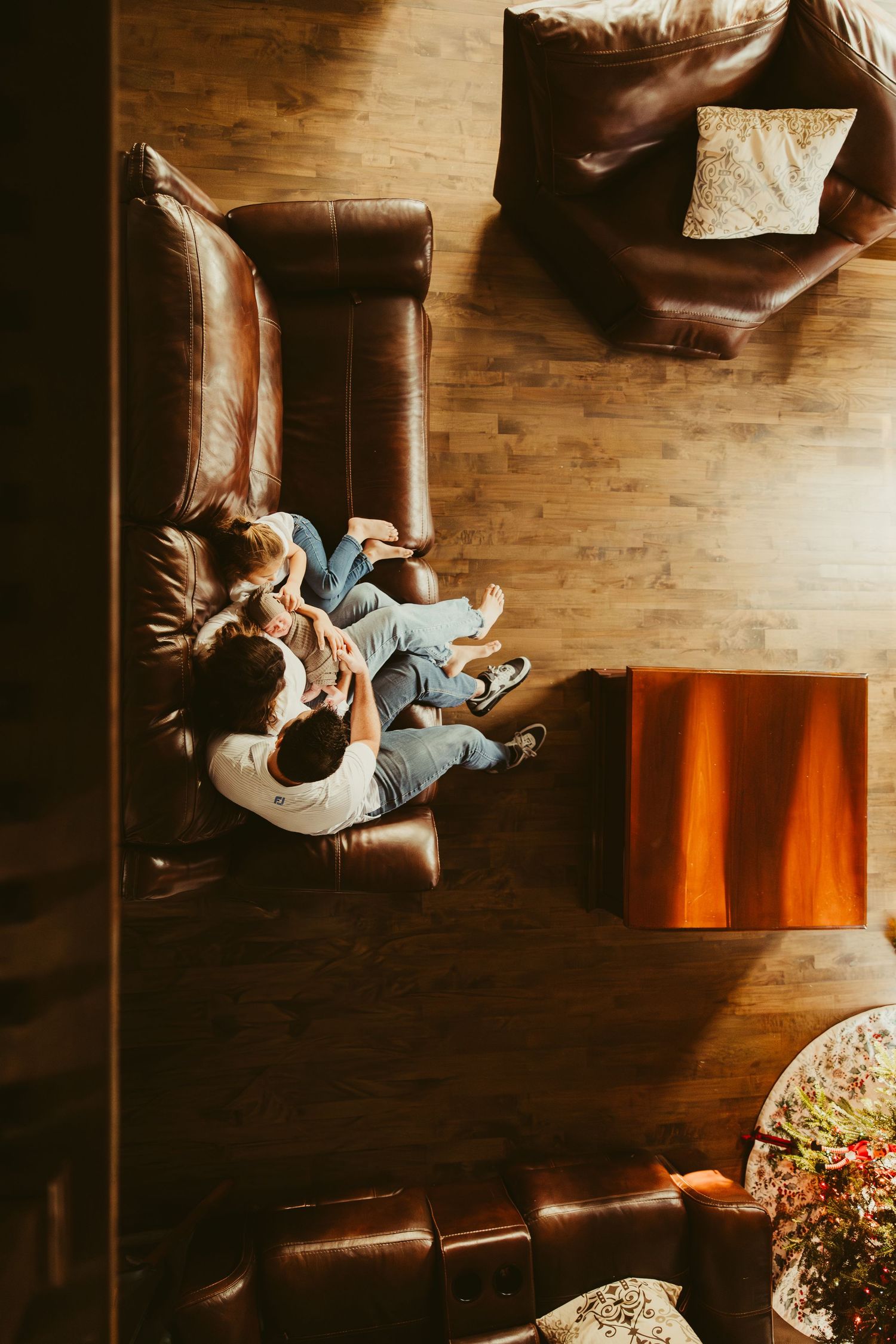 Overhead view of couple relaxing together on brown leather couch in warm sunlit living room.