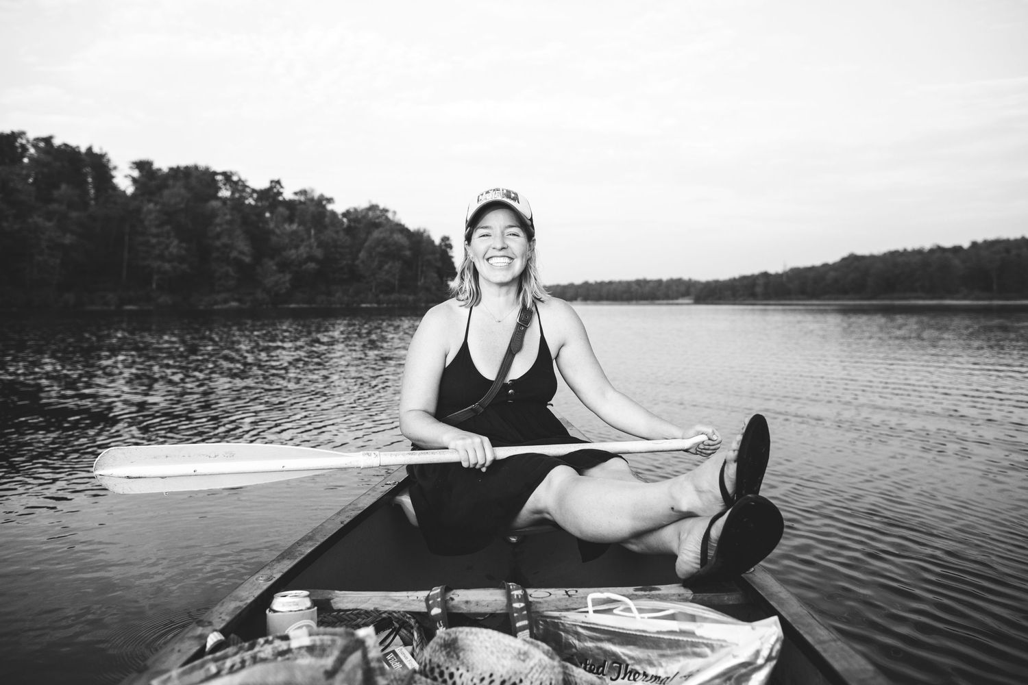 Black and white photos of someone relaxing on a paddleboard on a serene lake.