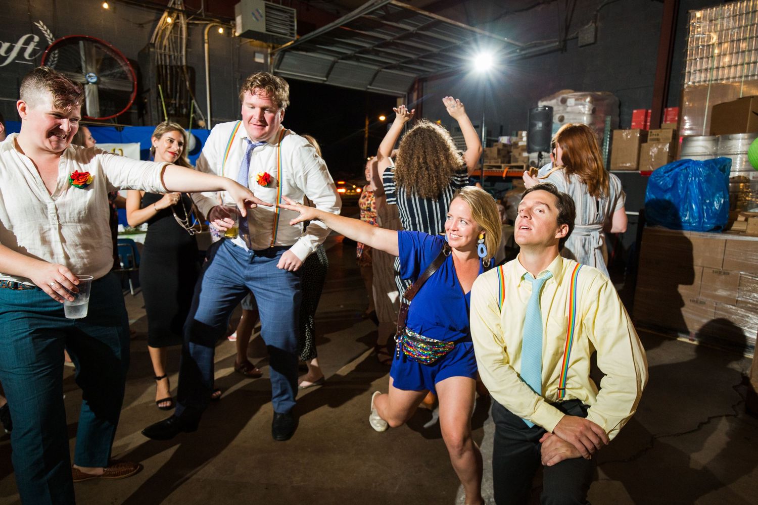 People dancing and celebrating at a dimly lit indoor party venue with industrial decor.
