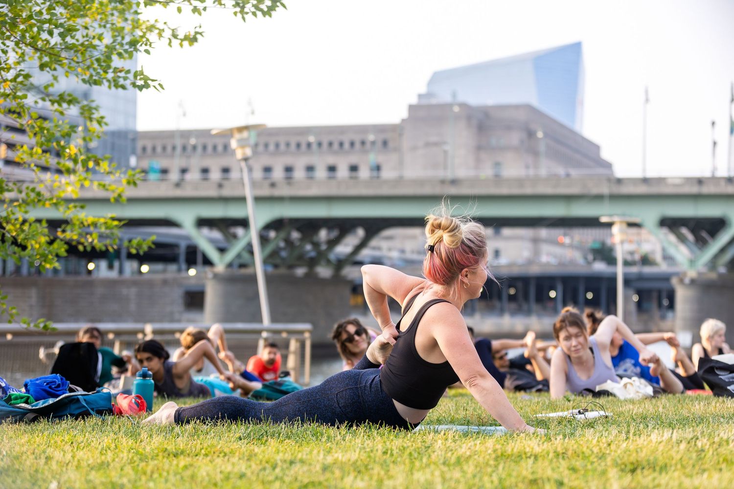 Outdoor fitness enthusiast stretches on grass near urban architecture.
