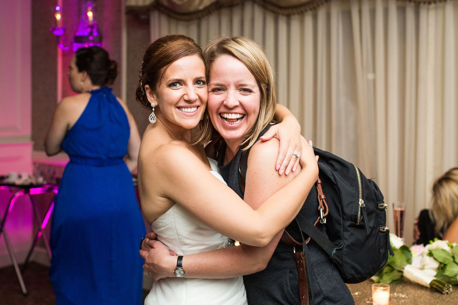Wedding reception guests sharing joyful embraces and laughter during the celebration.