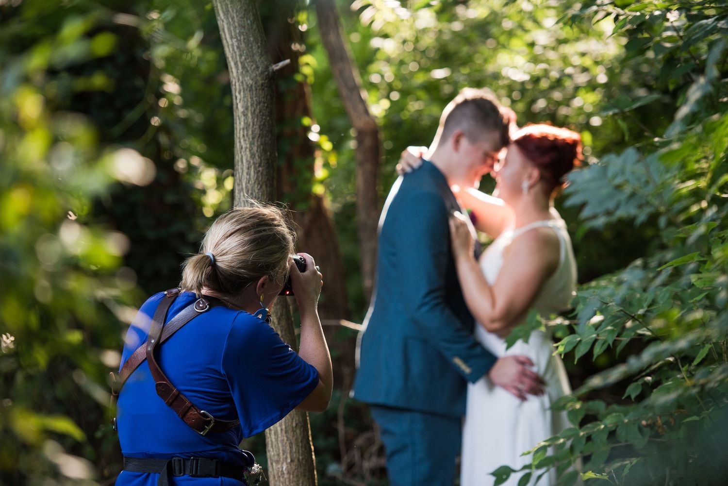 Wedding party posing for outdoor photos among green trees and natural scenery.