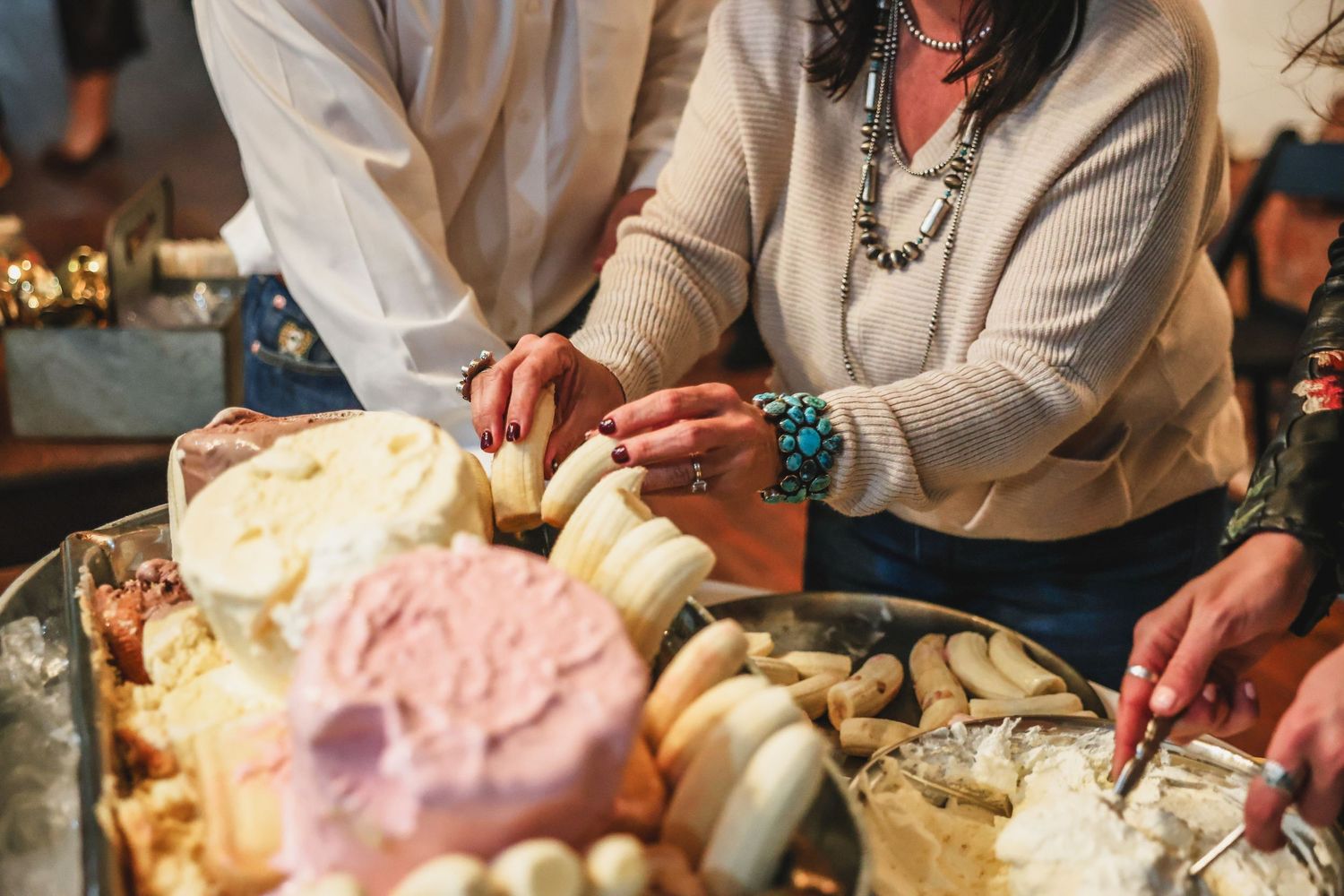 Guests selecting from a large charcuterie board featuring cheeses and crackers at an elegant catered gathering.