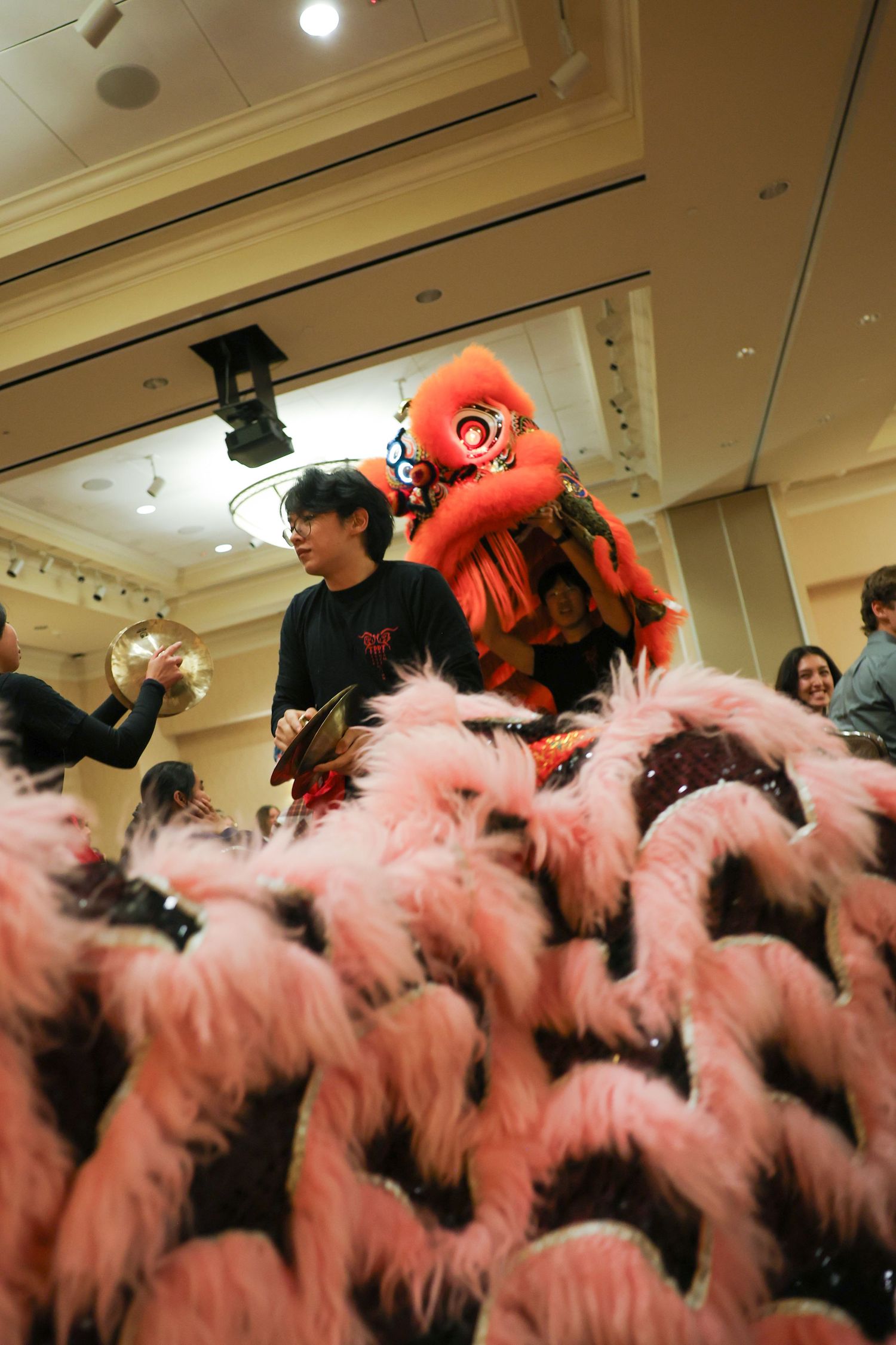Performer operates a pink Chinese lion dance costume up close during a traditional cultural celebration indoors.
