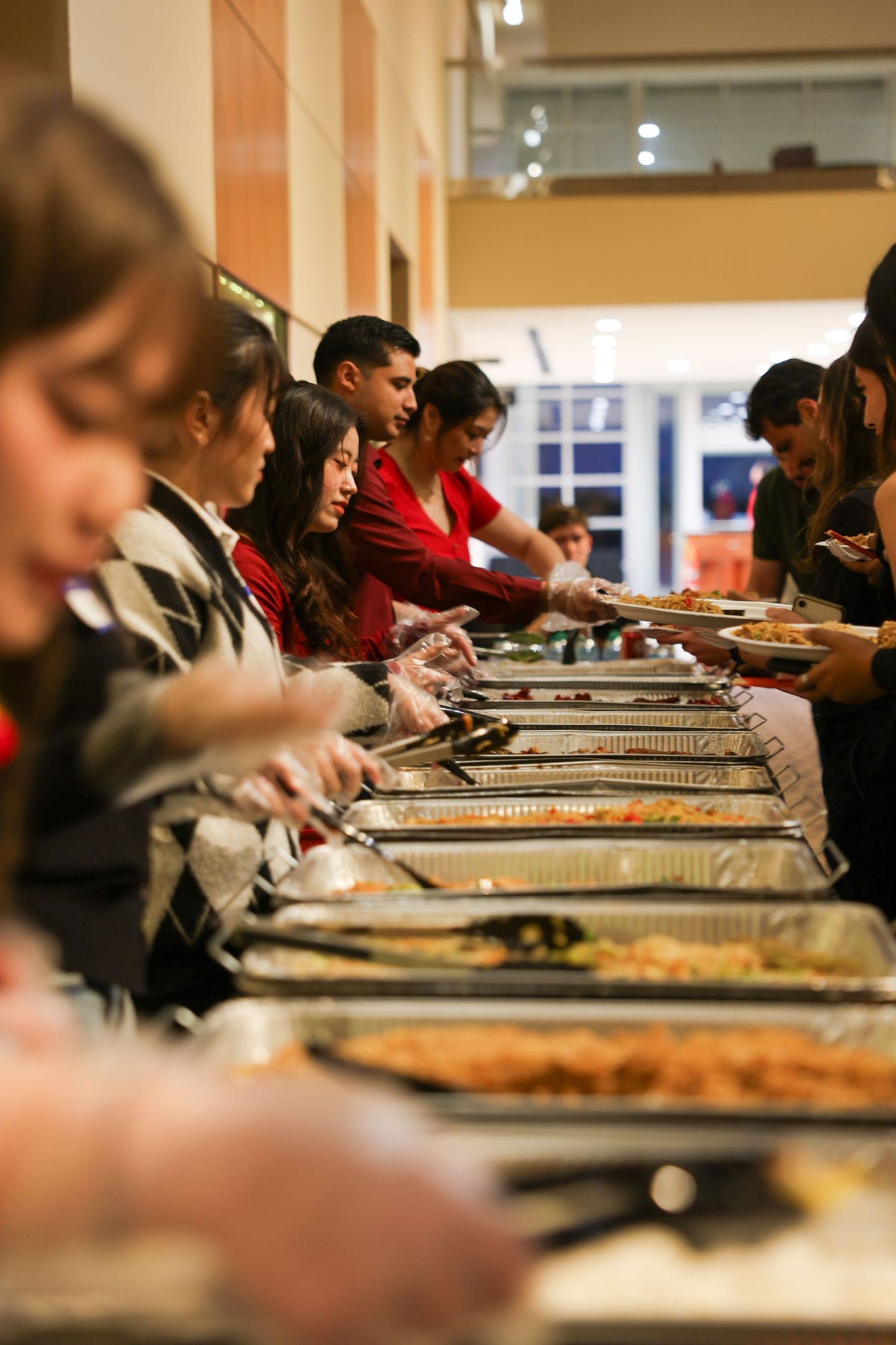 Diverse crowd of people serving themselves food at a large buffet line during a cultural celebration.