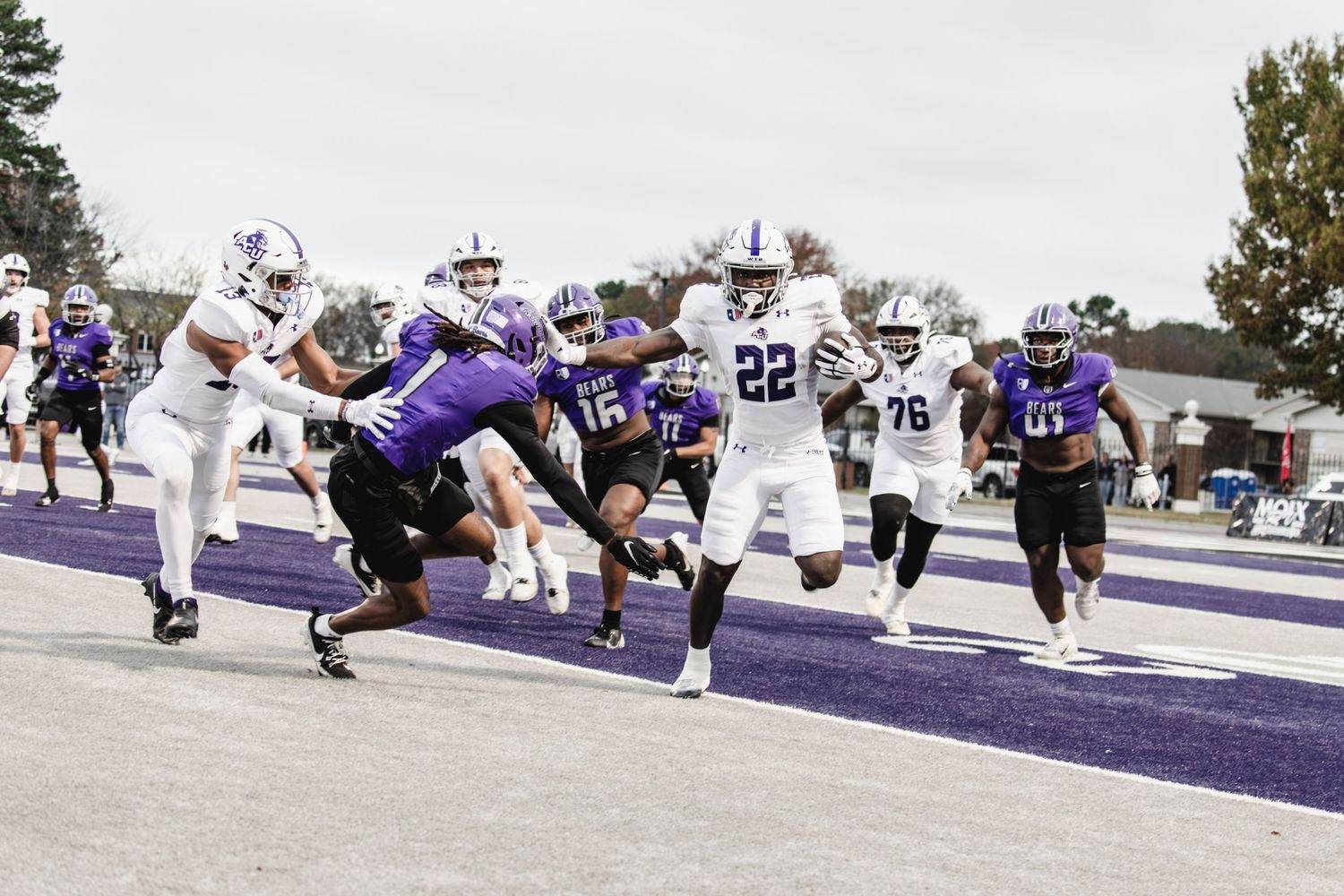 ACU football players pursue a ball carrier near the end zone during a game.