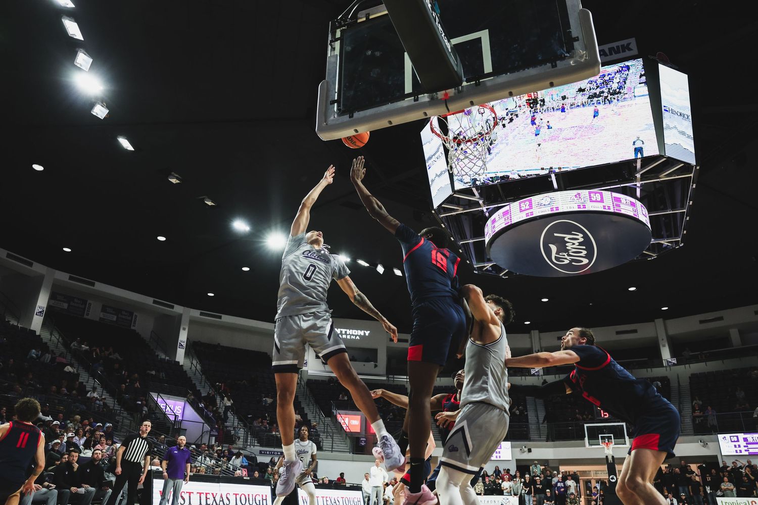 Texas Tech player throws down a powerful dunk over Abilene Christian defenders during a college basketball game.