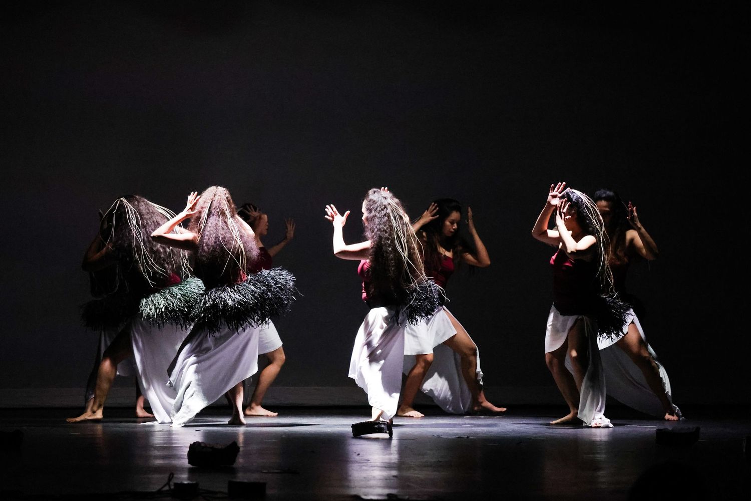 Dynamic dance performance with performers in dramatic poses on a darkly lit stage.
