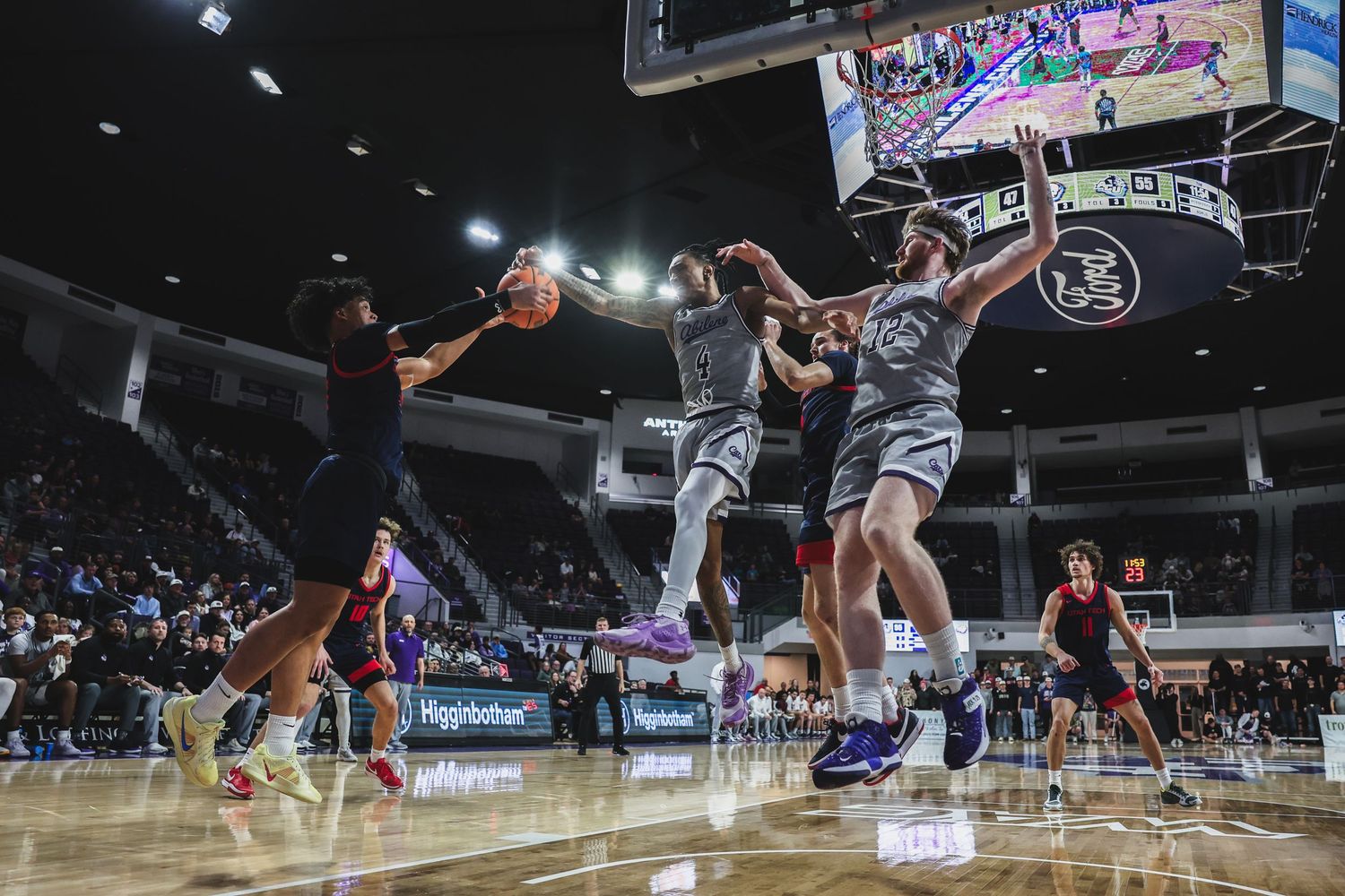 College basketball players battle for a rebound during an intense game between Abilene Christian and Texas Tech.