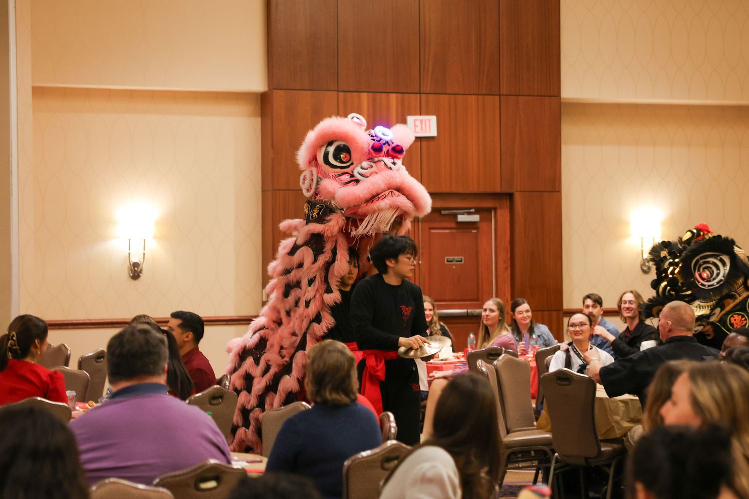 A colorful Chinese lion dance performance entertains guests at a Lunar New Year banquet in a hotel ballroom.
