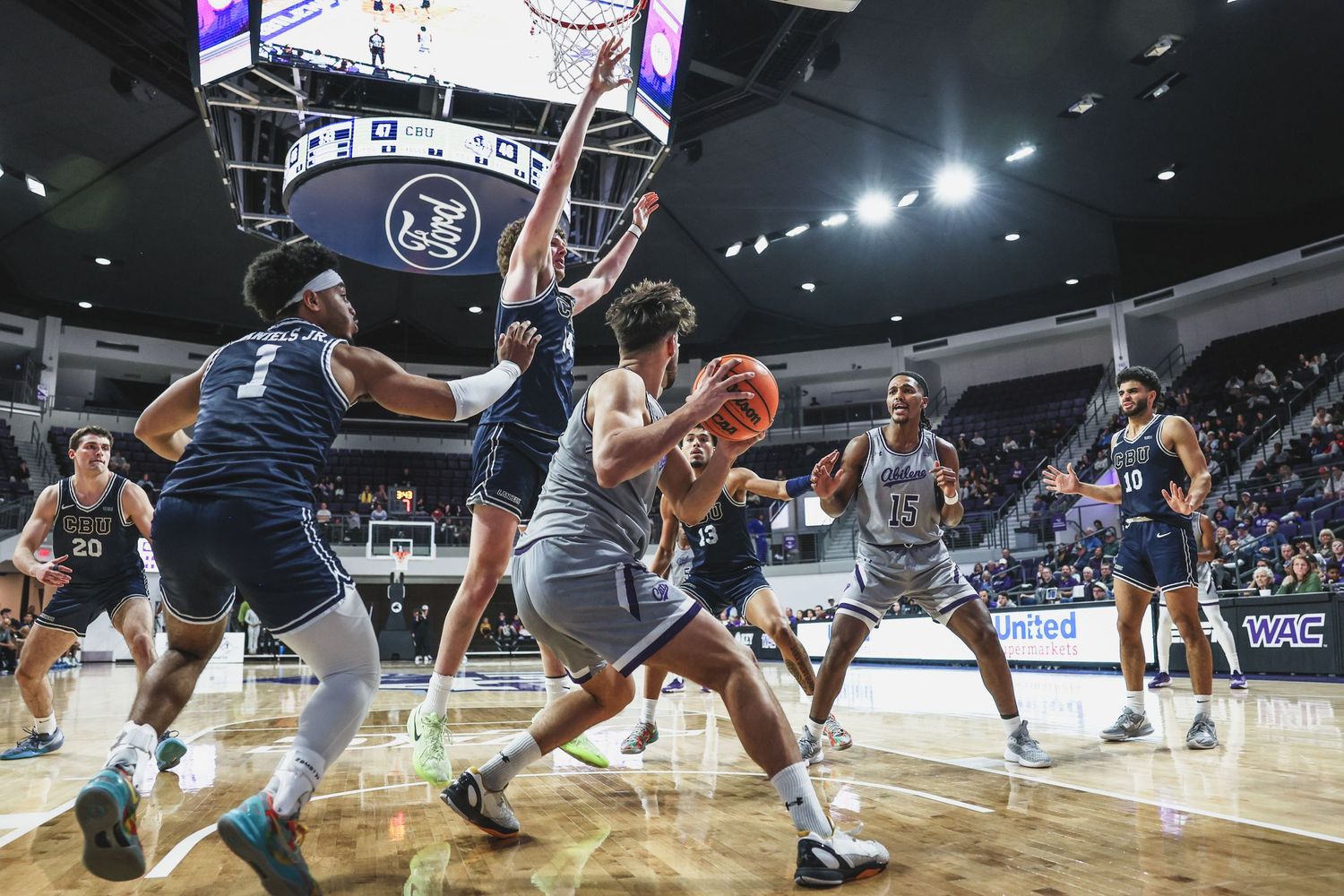 College basketball players battle for position under the basket during an indoor arena game.