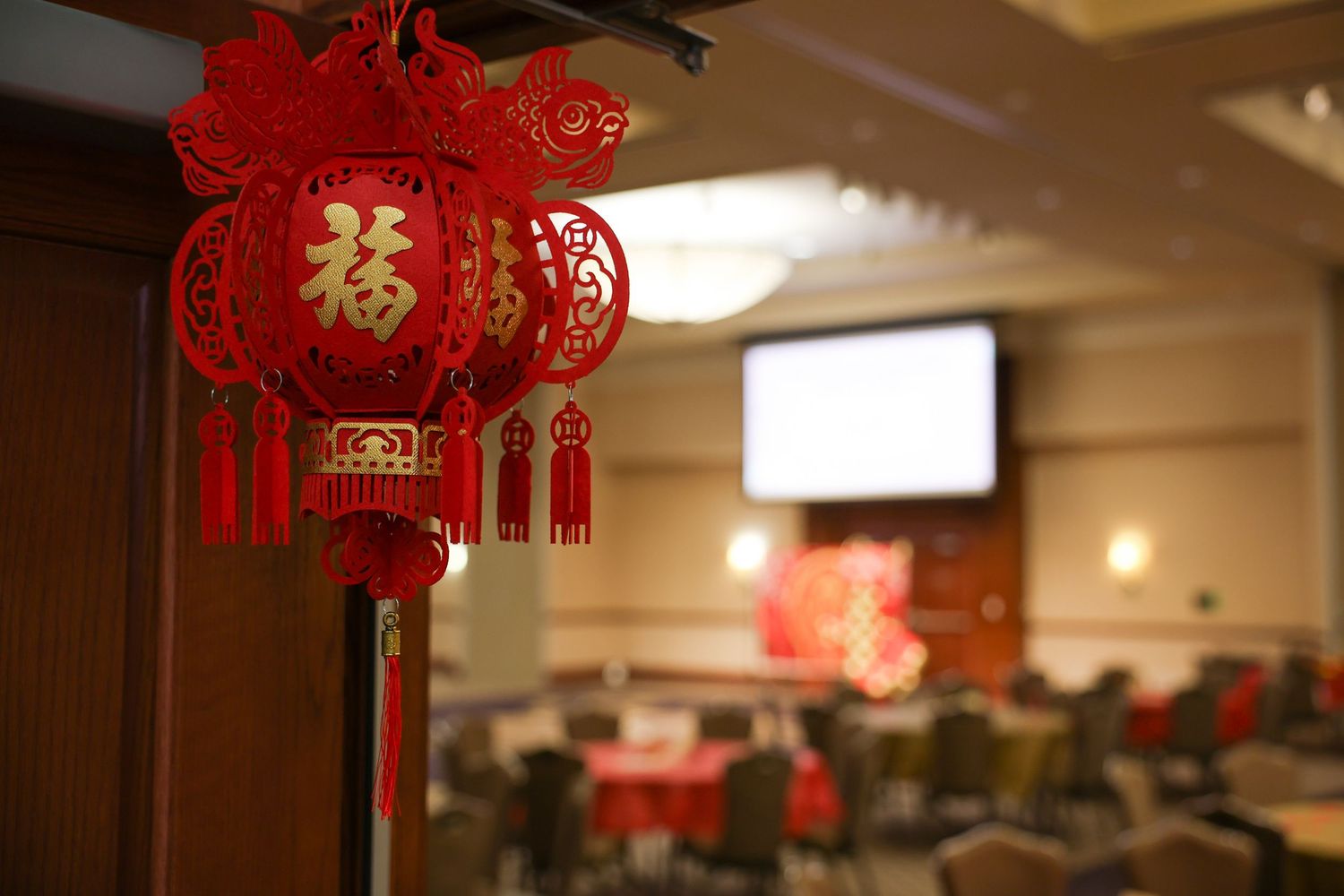 Red Chinese paper lanterns with gold Fu characters decorating a banquet hall for Lunar New Year.