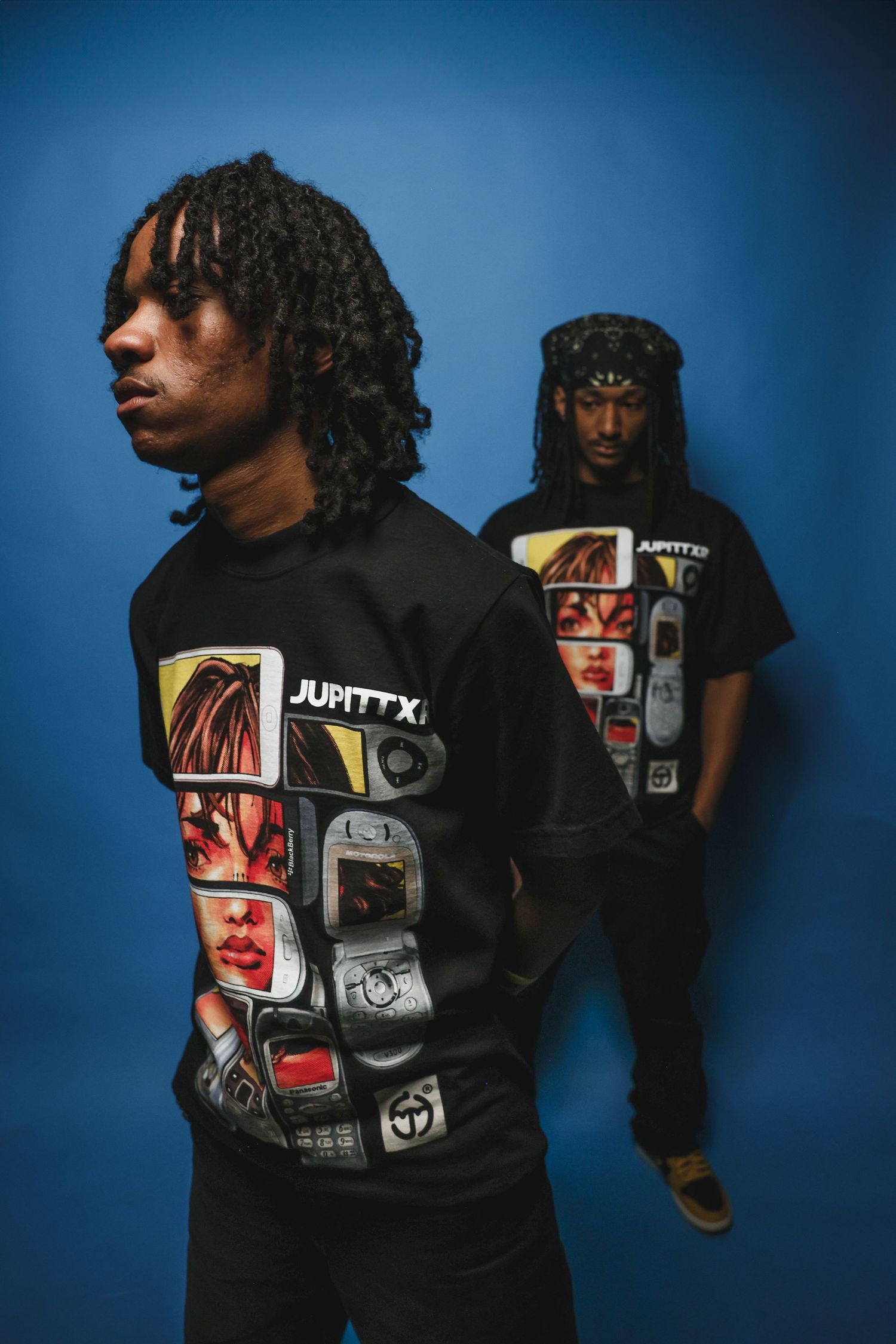 Two men wearing matching black JUPITTXR graphic sweatshirts pose against a blue background.
