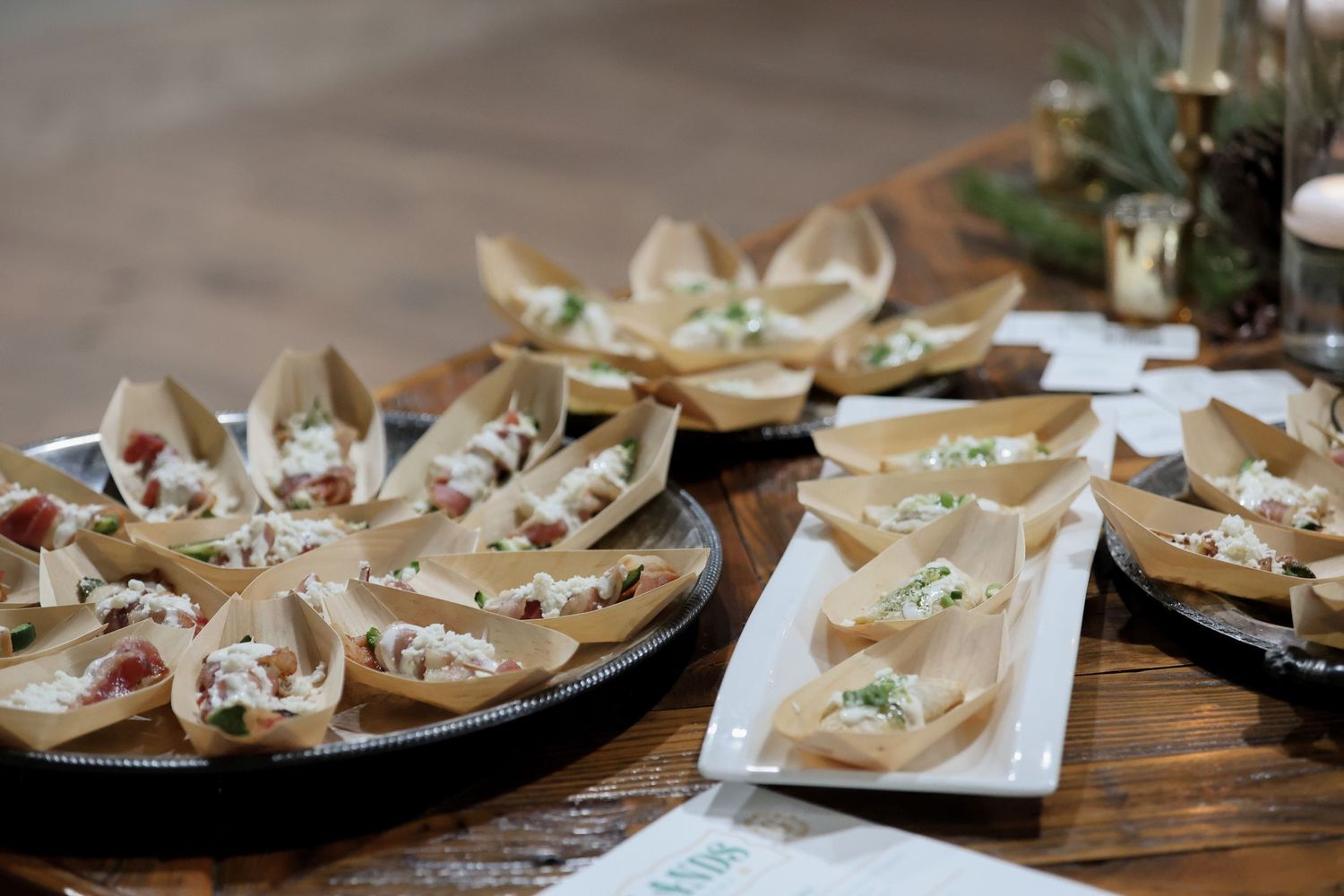 Elegant appetizers served in crispy wonton cups arranged on round and rectangular platters on a wooden table.