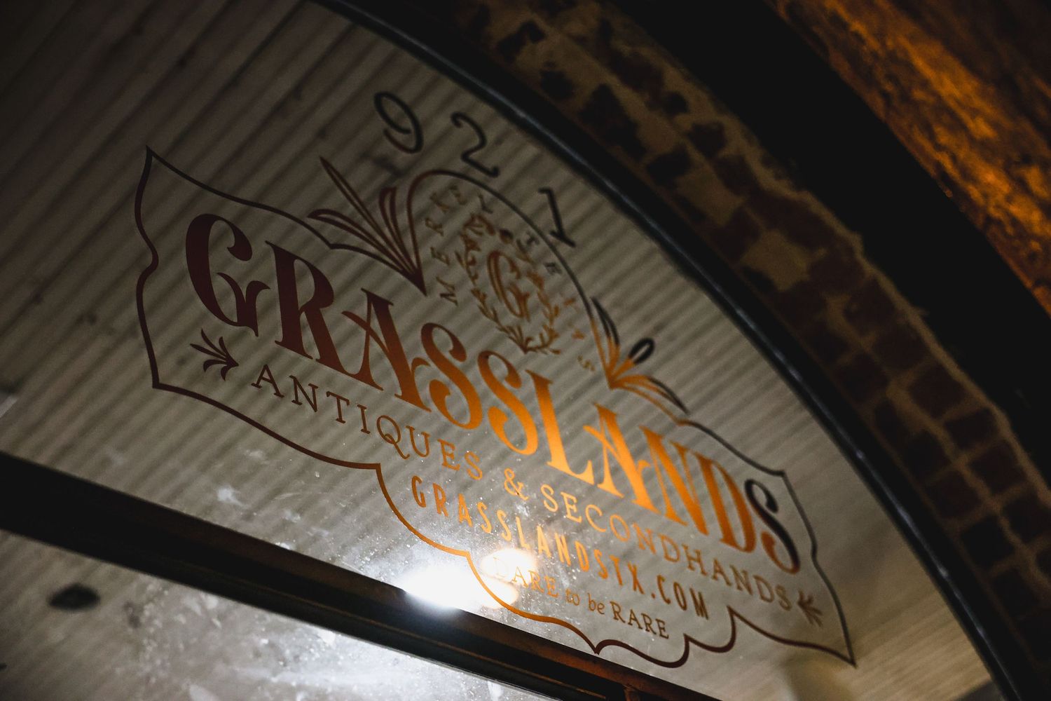 Vintage Grasslands Antiques and Secondhand store sign on rustic brick archway ceiling.