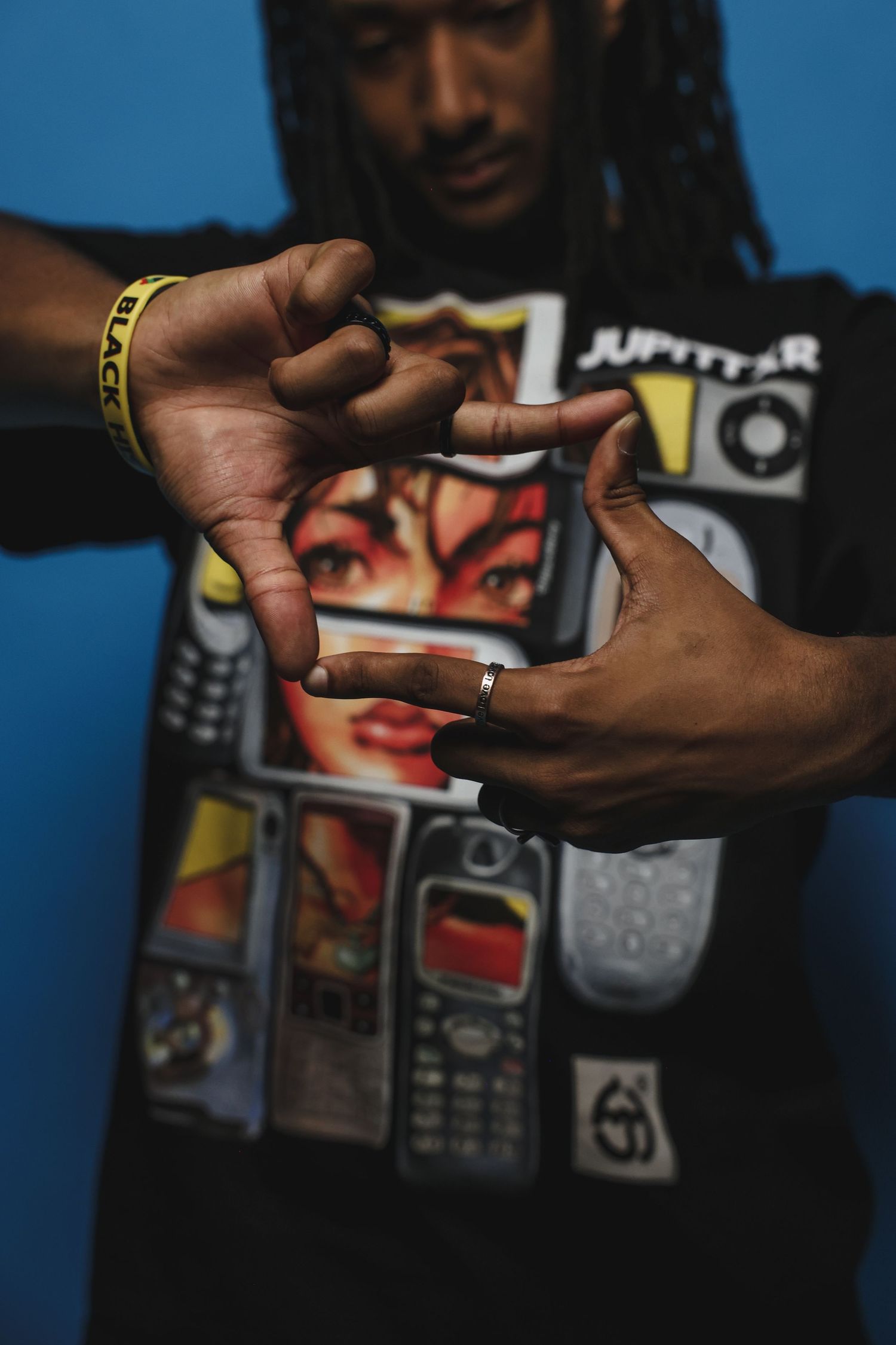 Close-up of man in Jupittar graphic tee forming a hand gesture toward the camera.