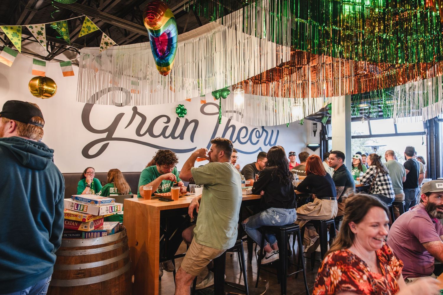 Lively interior of Grain Theory brewery decorated for St. Patrick's Day with festive streamers.