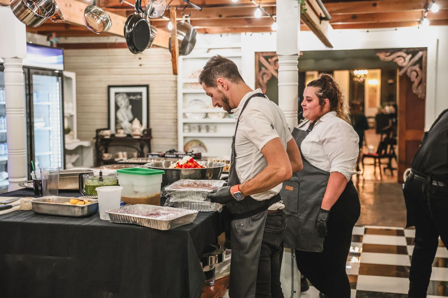 Two catering chefs preparing food at a kitchen station during a catered event.