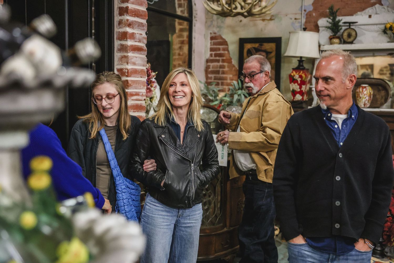 Group of smiling guests enjoying a catered event inside a rustic brick venue.