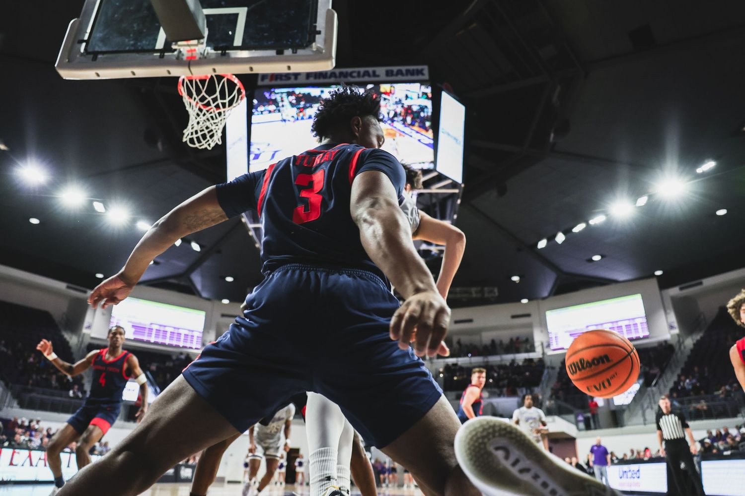 Low-angle view of basketball player number 3 in red and blue uniform positioning near the basket.