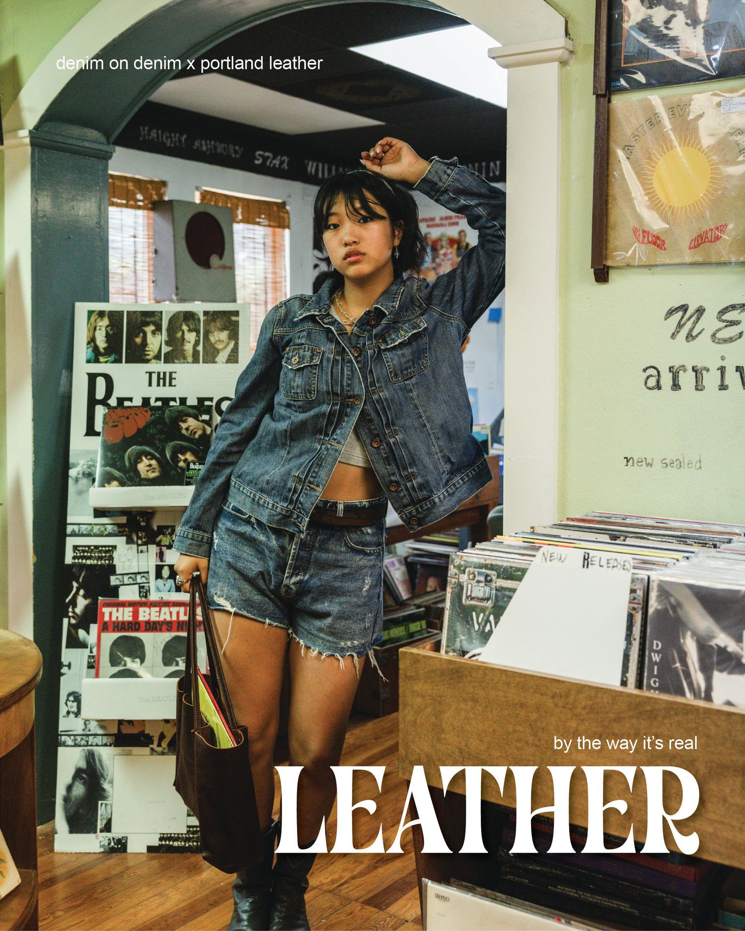 Woman in denim jacket and shorts poses in a record store for Denim on Denim x Portland Leather campaign.