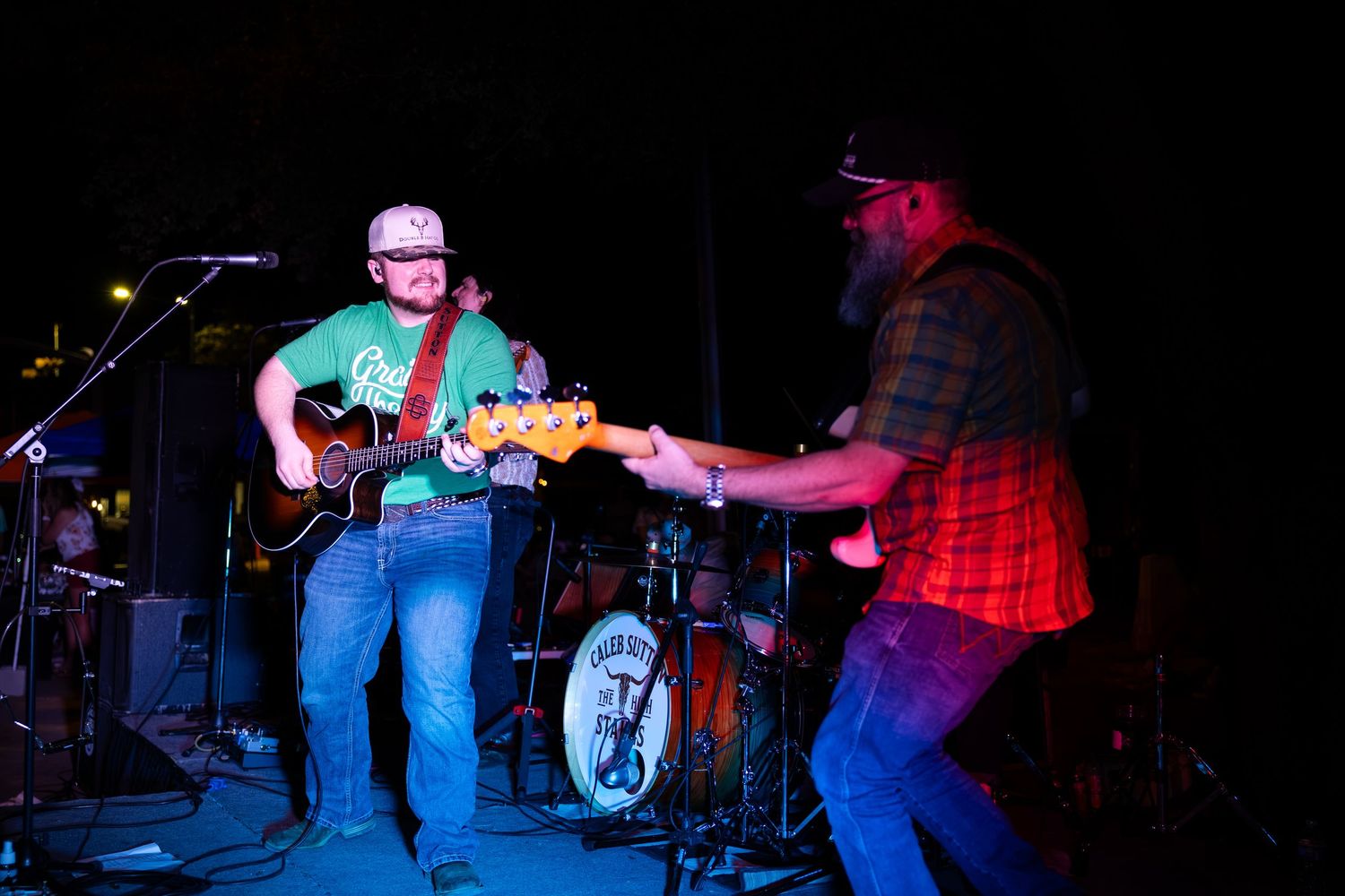 Two musicians playing guitars together on stage during energetic live band performance at night.