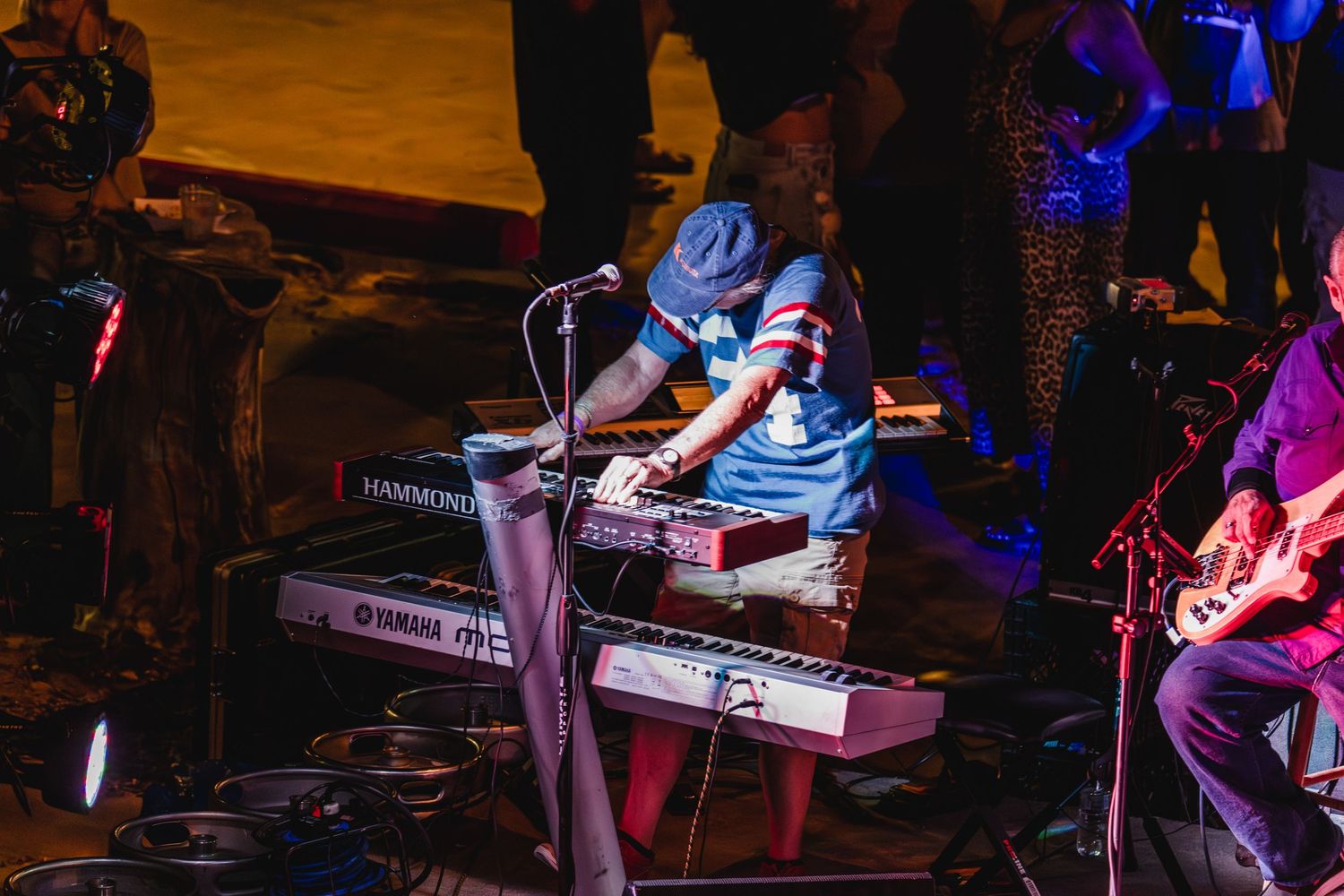 Musician playing Yamaha keyboard on stage with microphone during a live outdoor performance.