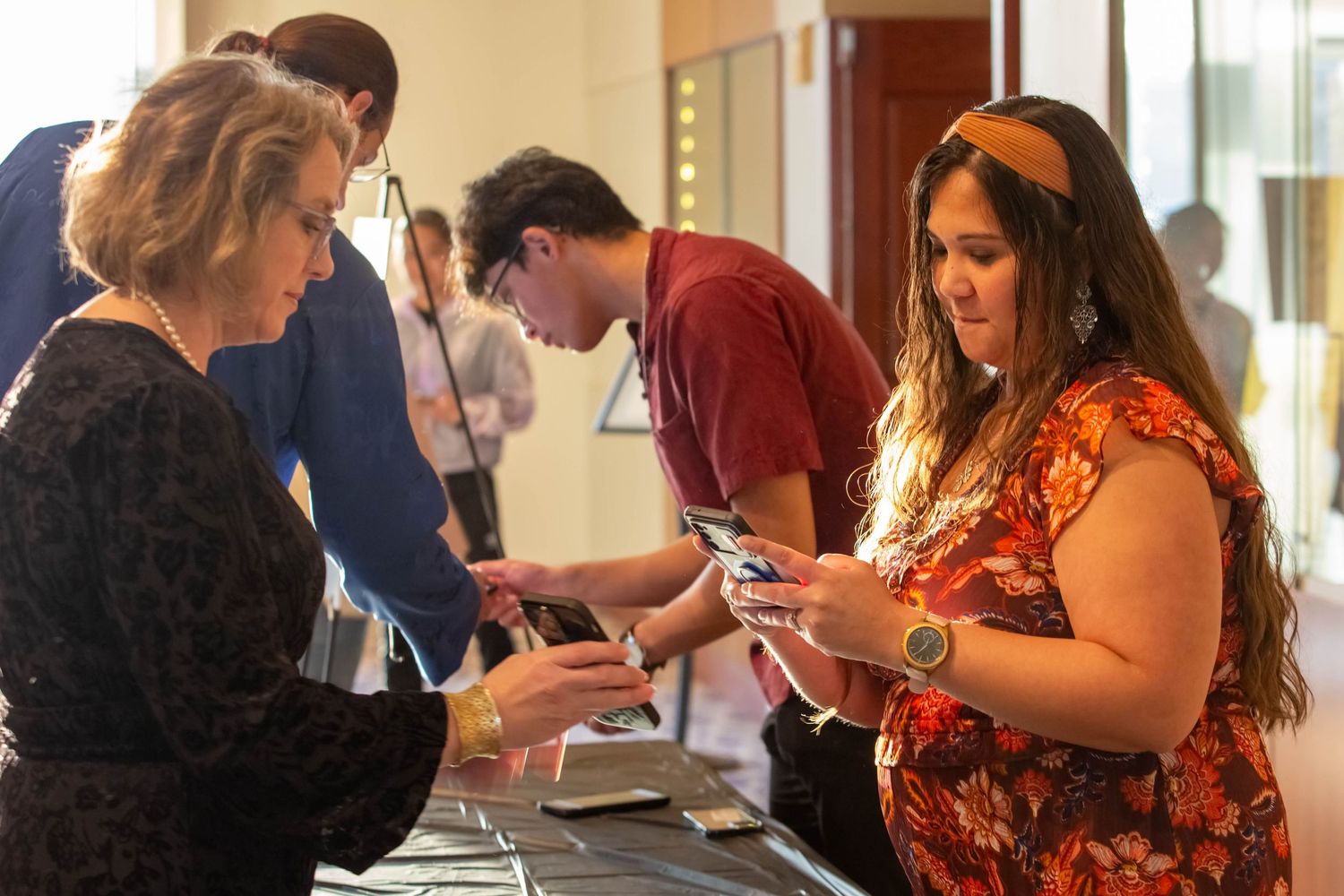 Attendees check in at a registration table at a multicultural student event using mobile devices.