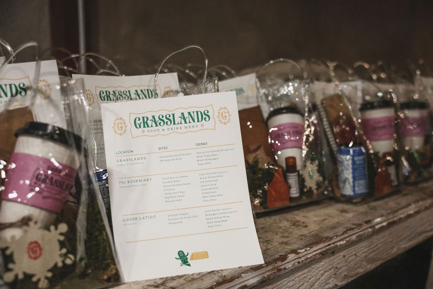 Grasslands gift bags with menus and local products displayed on a rustic wooden shelf.