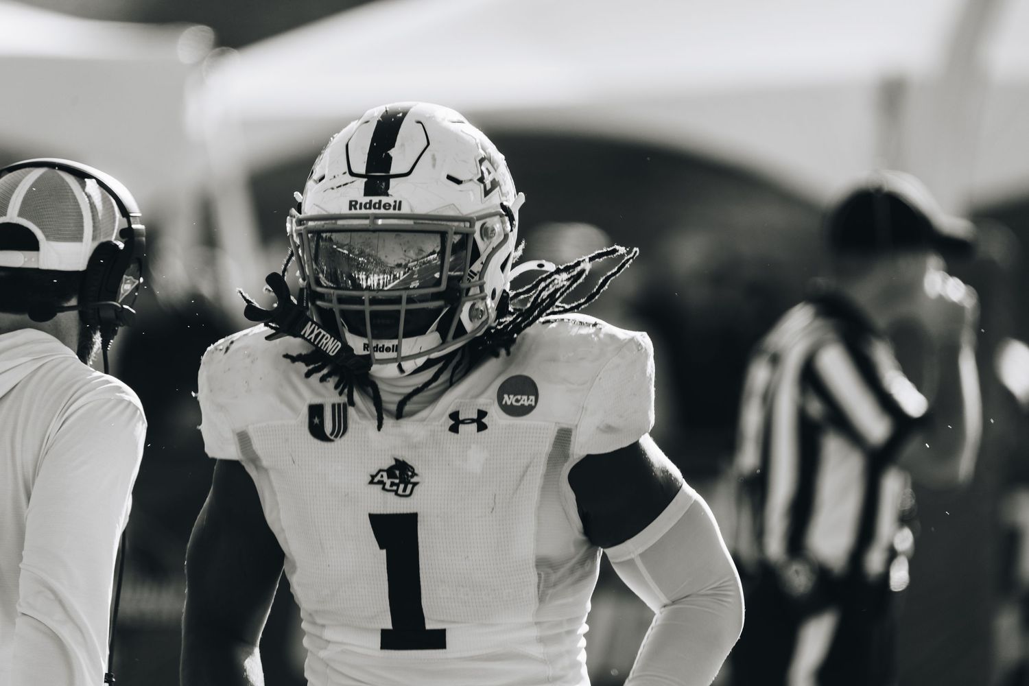 Black and white photo of ACU football player #1 in helmet and pads on the sideline.