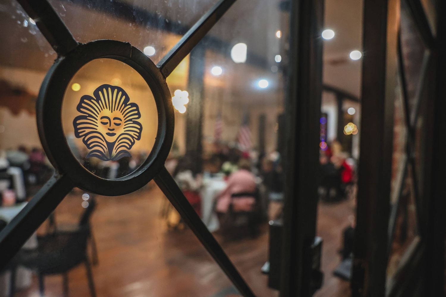 Ornate metal door detail with sun face medallion overlooking a warmly lit dining room.