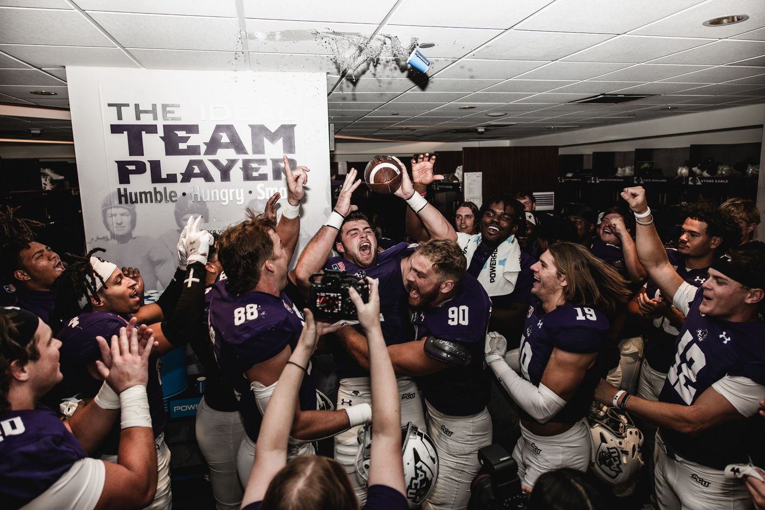 ACU football team celebrates enthusiastically in the locker room after a big win.