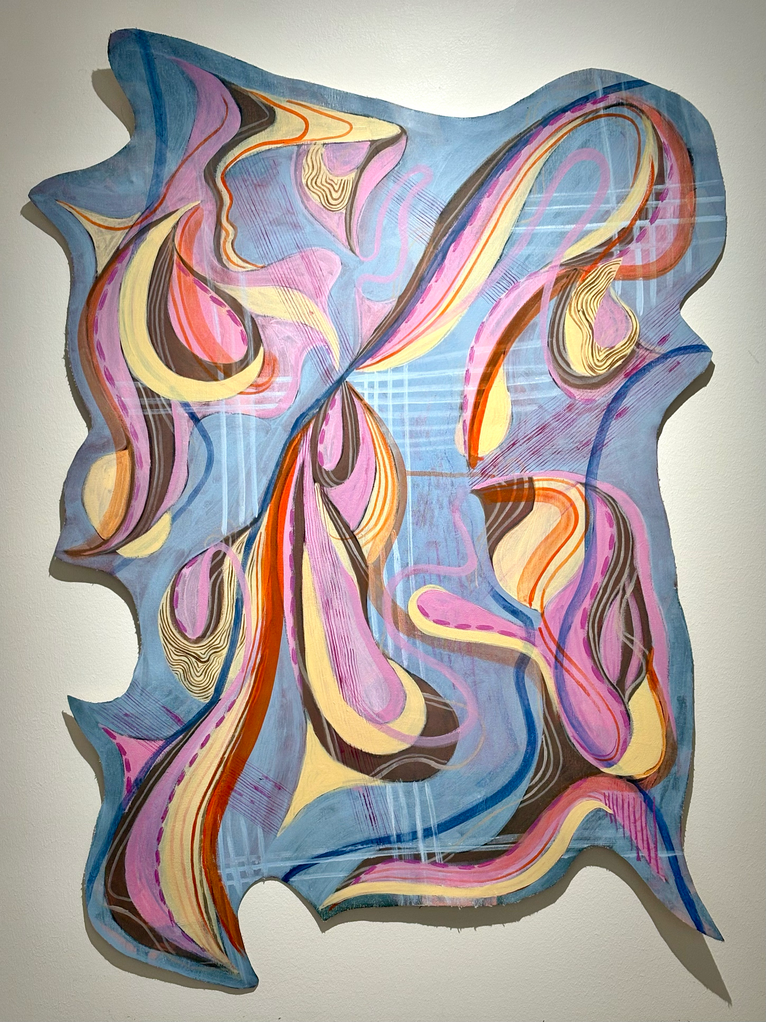 Abstract painting with swirling pink, yellow, and brown forms on a blue background, displayed on a gallery wall.
