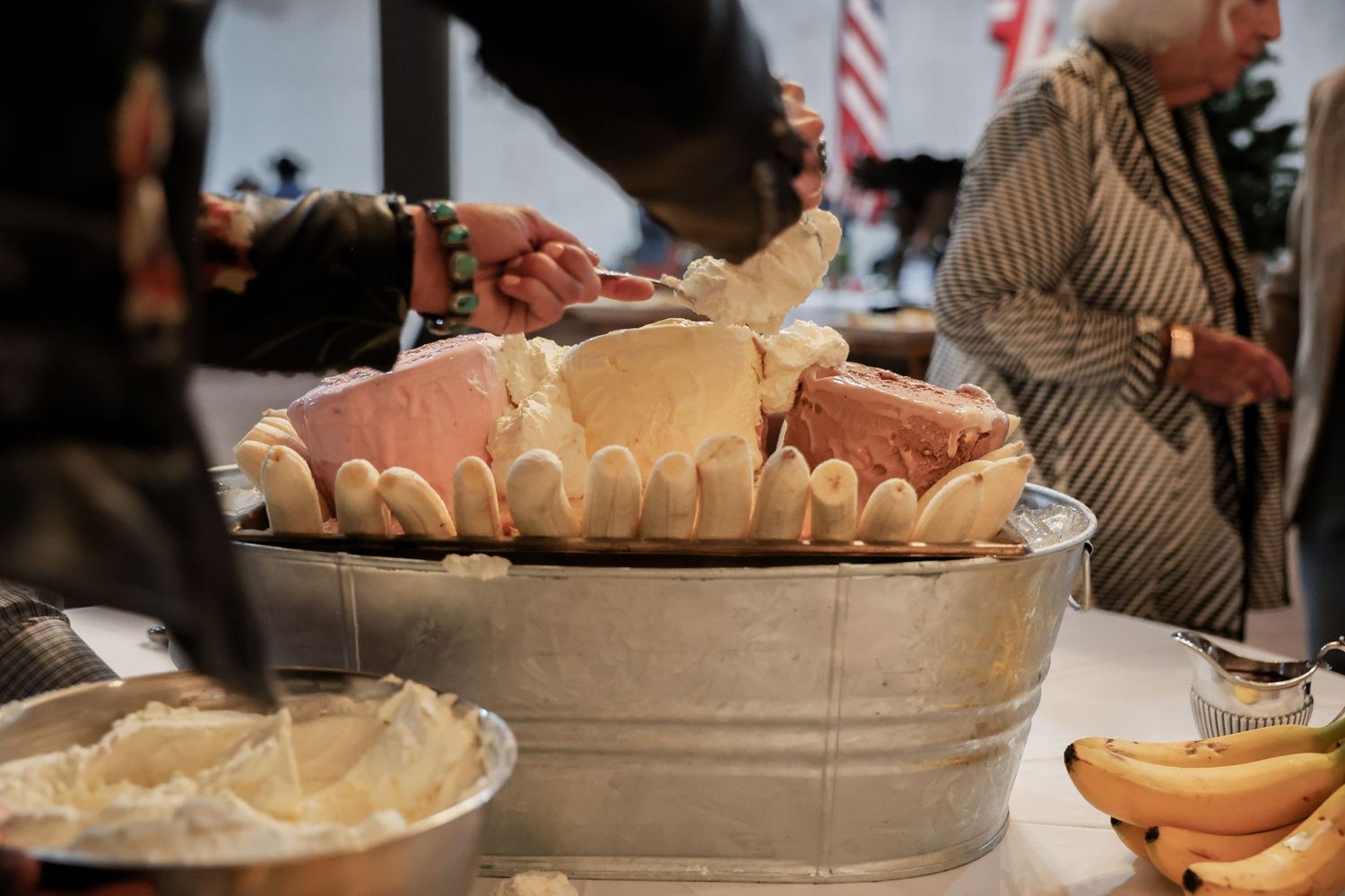 Close-up of a galvanized tub overflowing with assorted cheeses and bread at an upscale food tasting event.