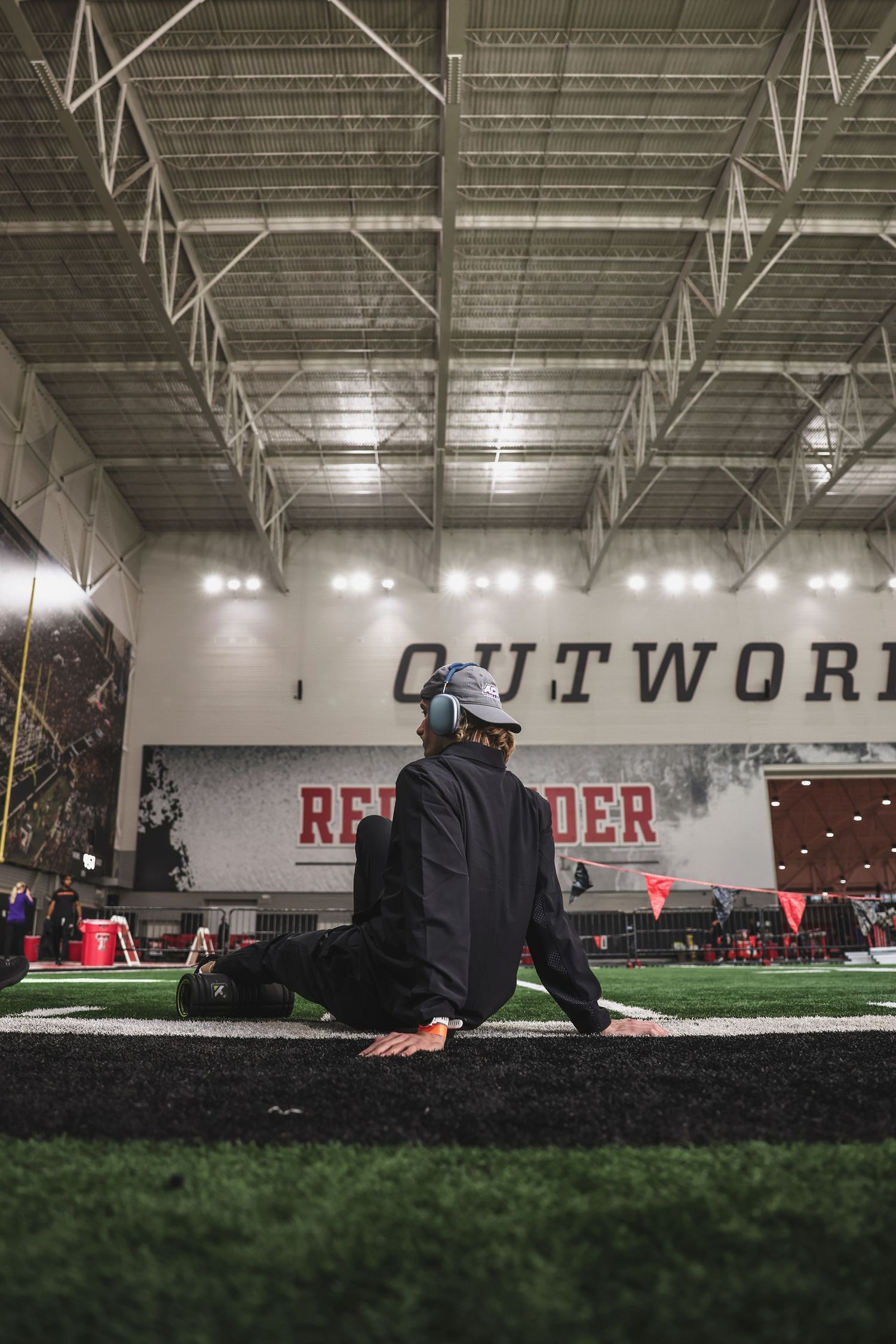 Athlete stretching on turf inside Texas Tech Red Raiders indoor facility with motivational wall text.