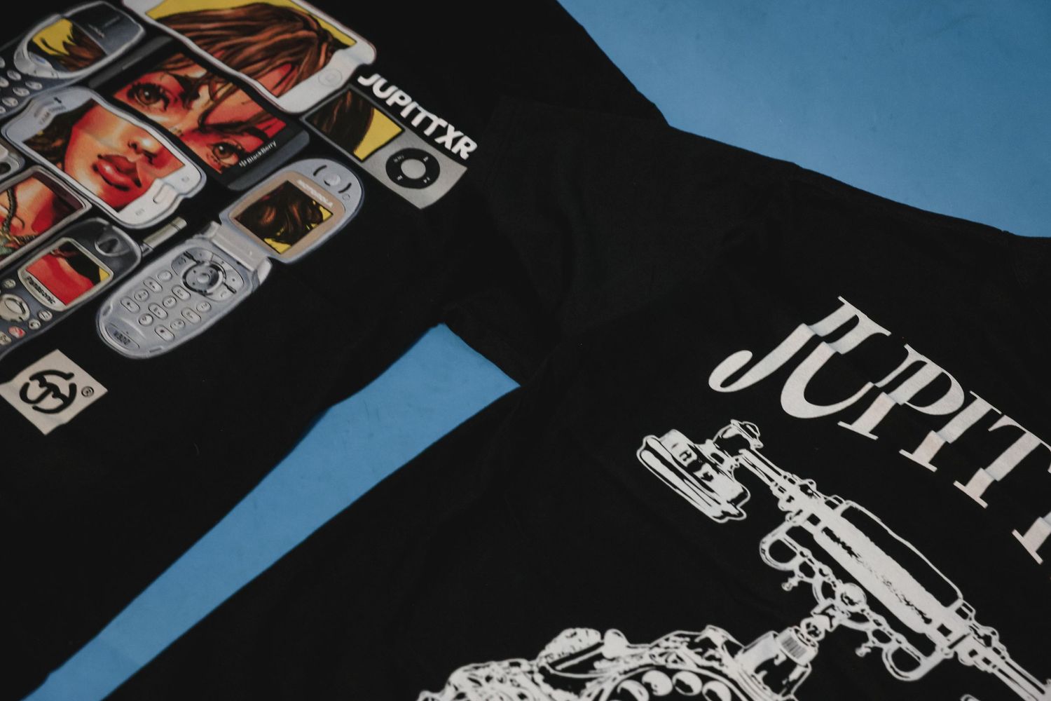 Close-up detail shot of two black Jupittar branded graphic t-shirts side by side.
