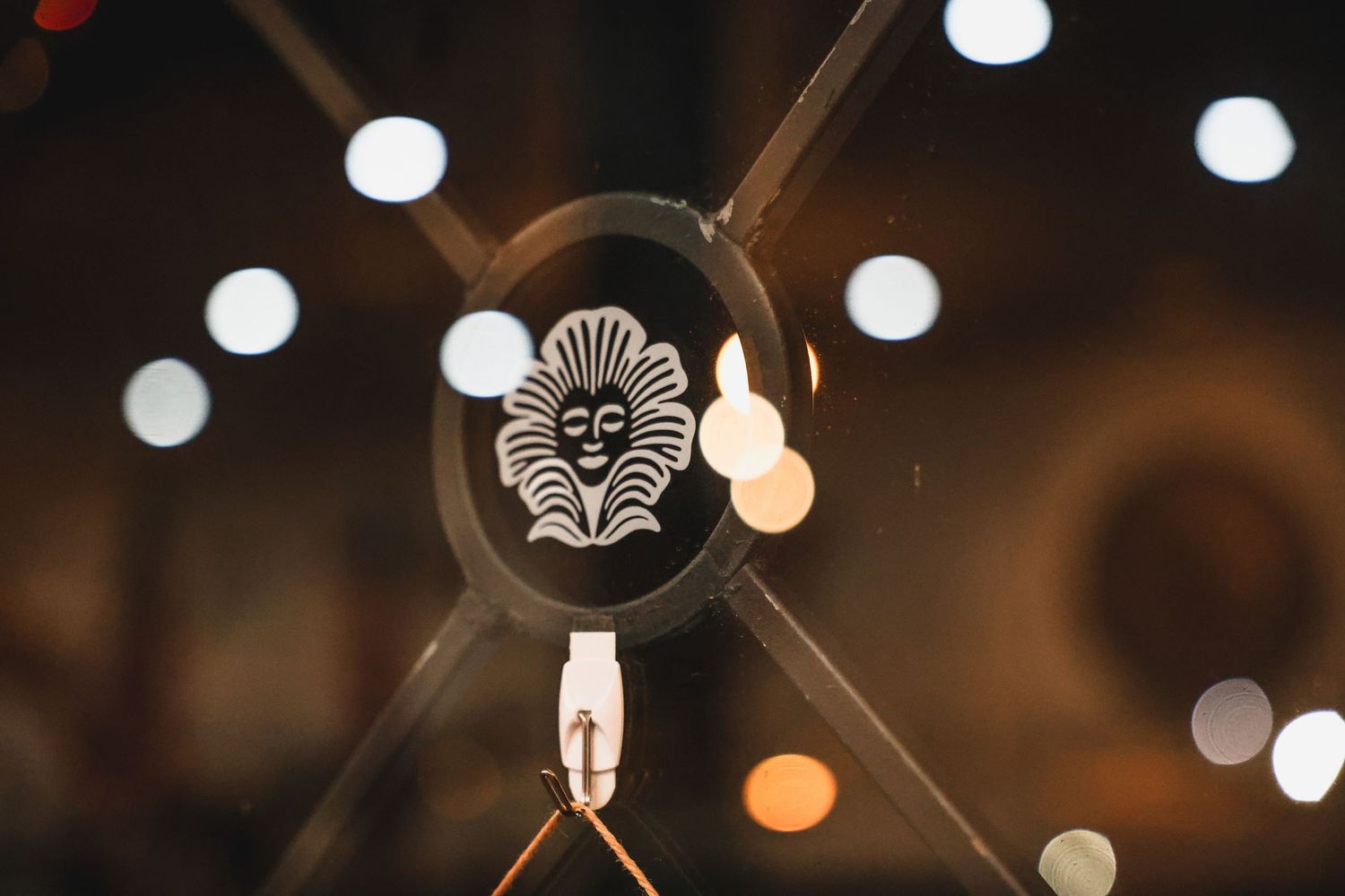 Decorative metal ornament featuring a sun face design with bokeh lights in the background.