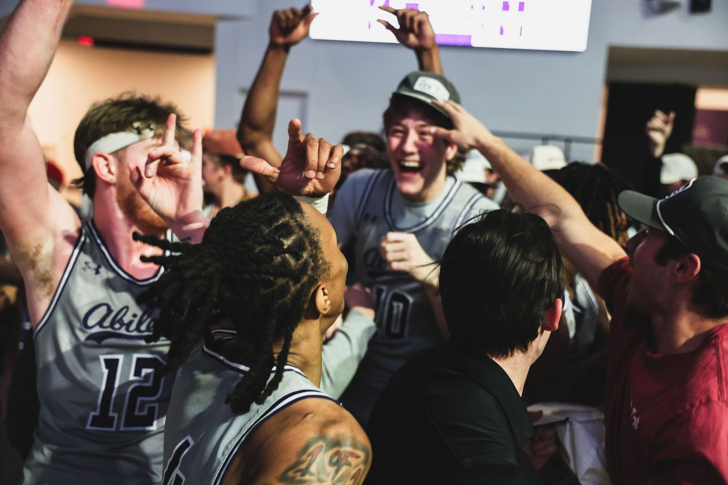 Basketball players and fans celebrate together in an energetic post-game victory celebration.