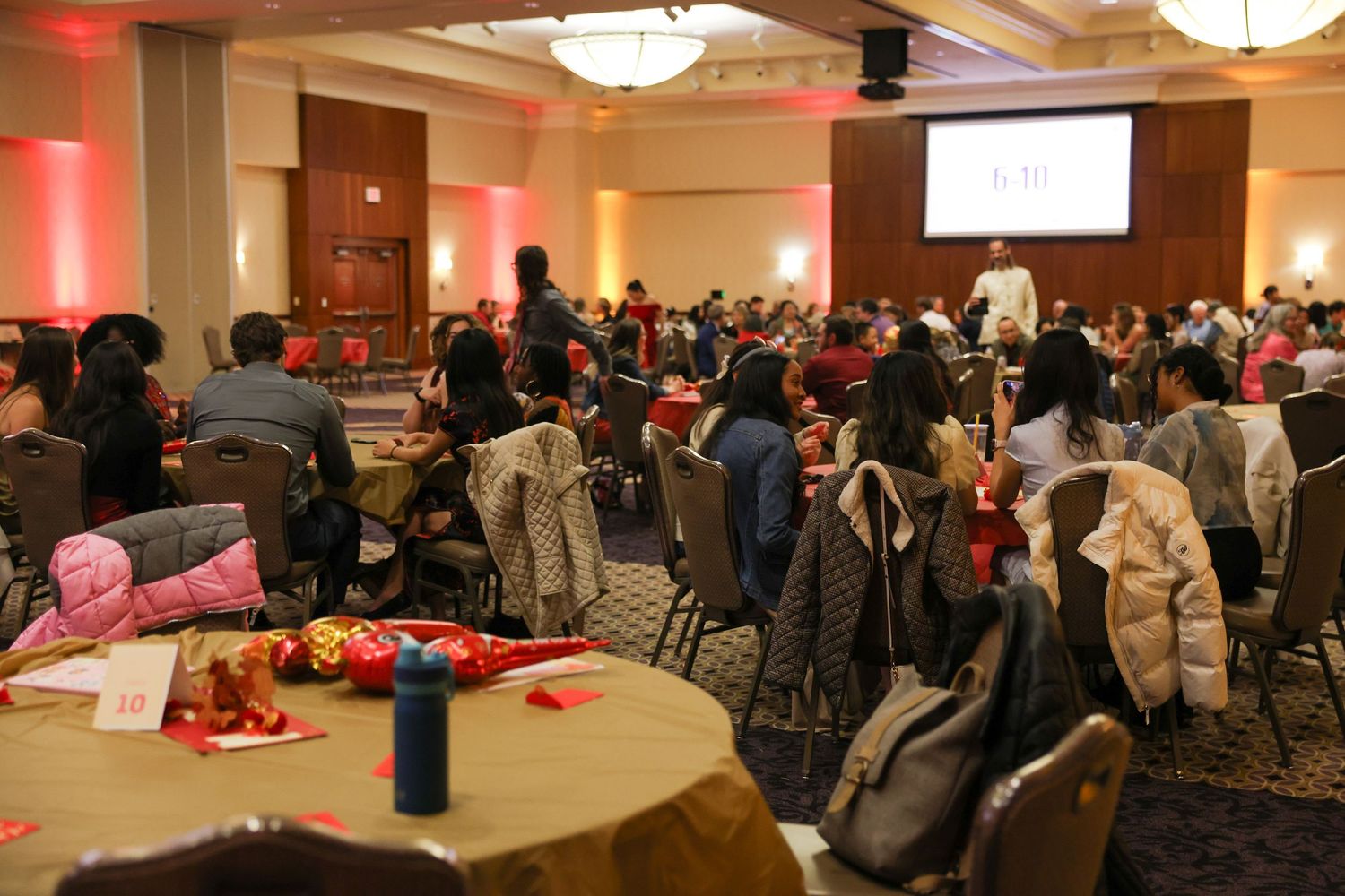 A large crowd of diverse attendees seated at round tables during a festive Lunar New Year celebration event.