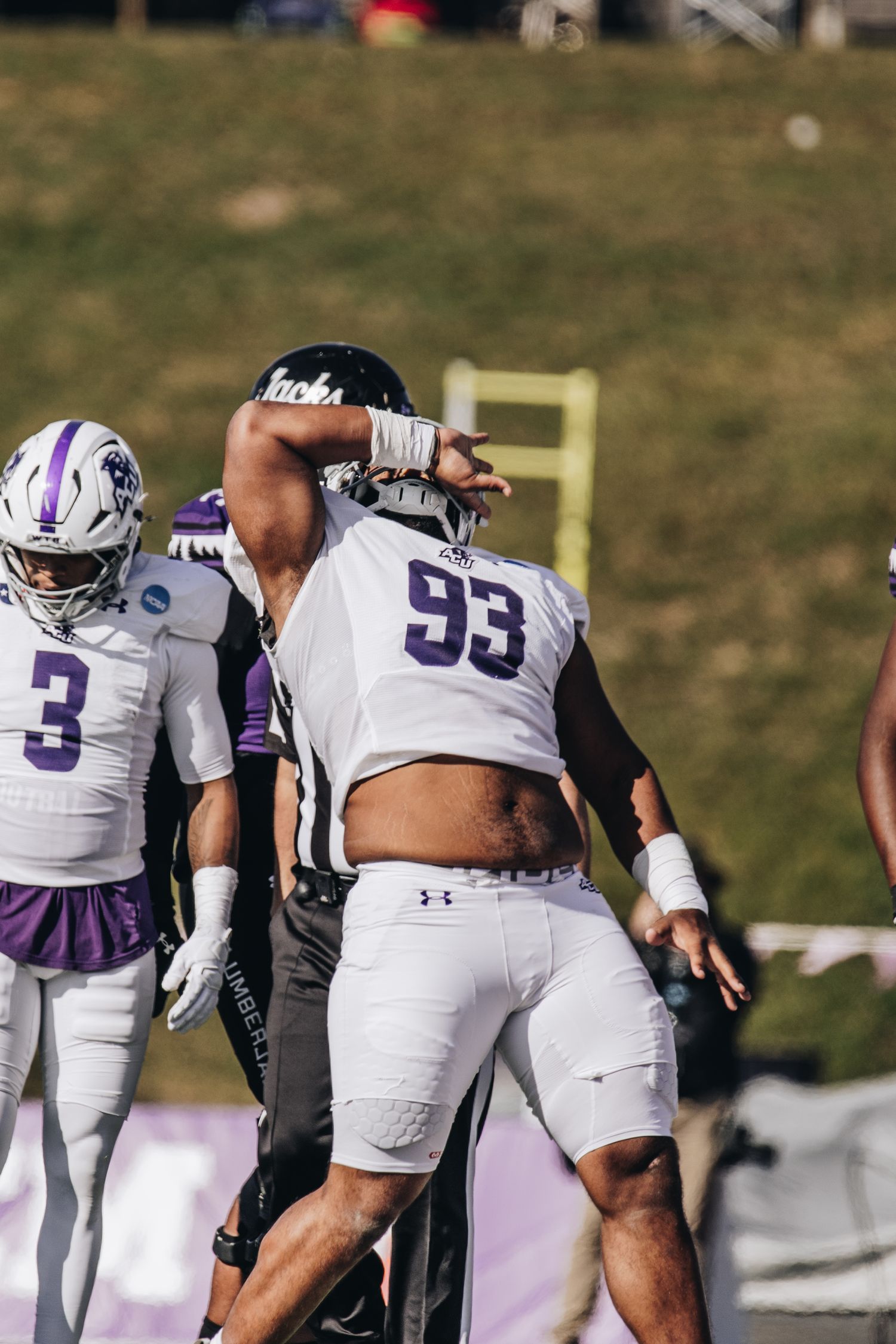 ACU football player #93 in white uniform celebrates during a college football game.