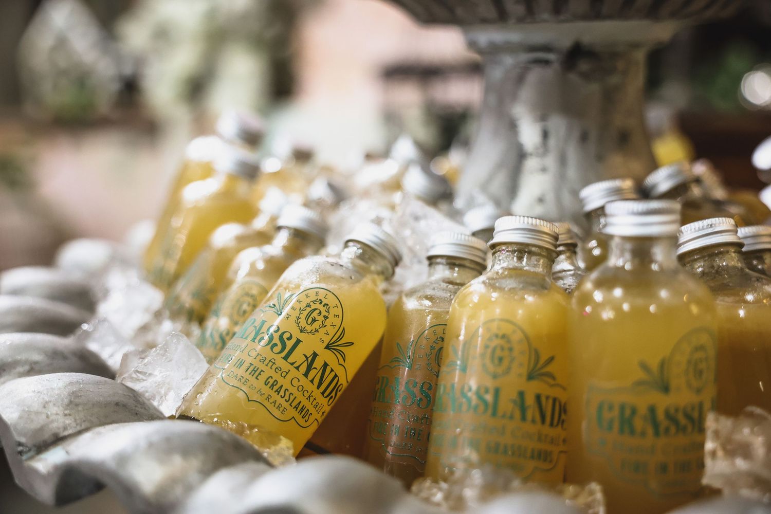 Grasslands branded glass bottles chilled on ice at a vintage-style market event.