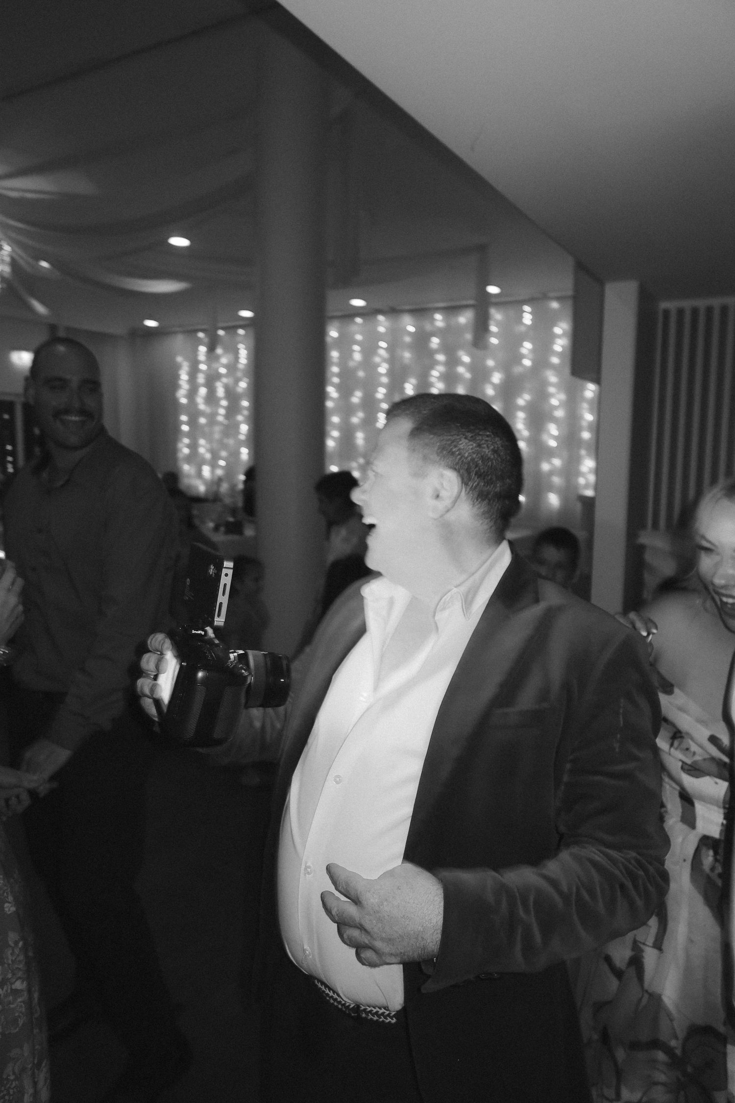 Wedding guest laughing and celebrating on the dance floor at evening reception.