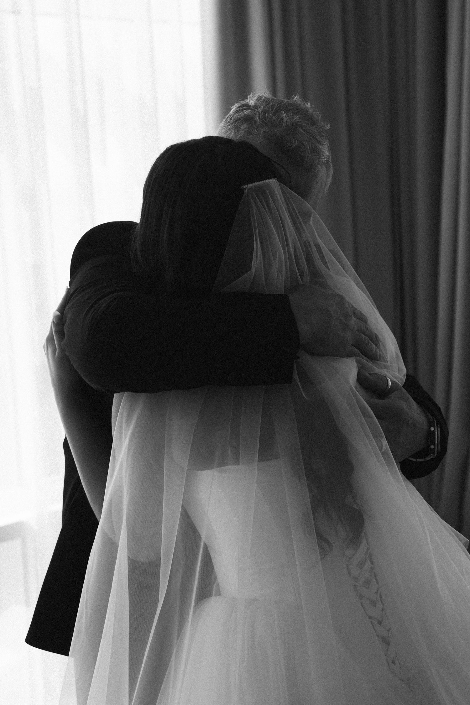 Emotional black and white photo of bride and father of the bride sharing tender wedding day embrace.