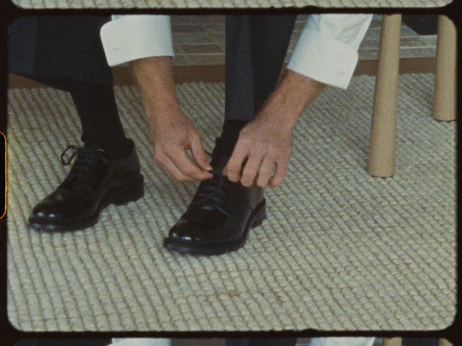 Groom tying his black dress shoes while seated, preparing for his wedding day.