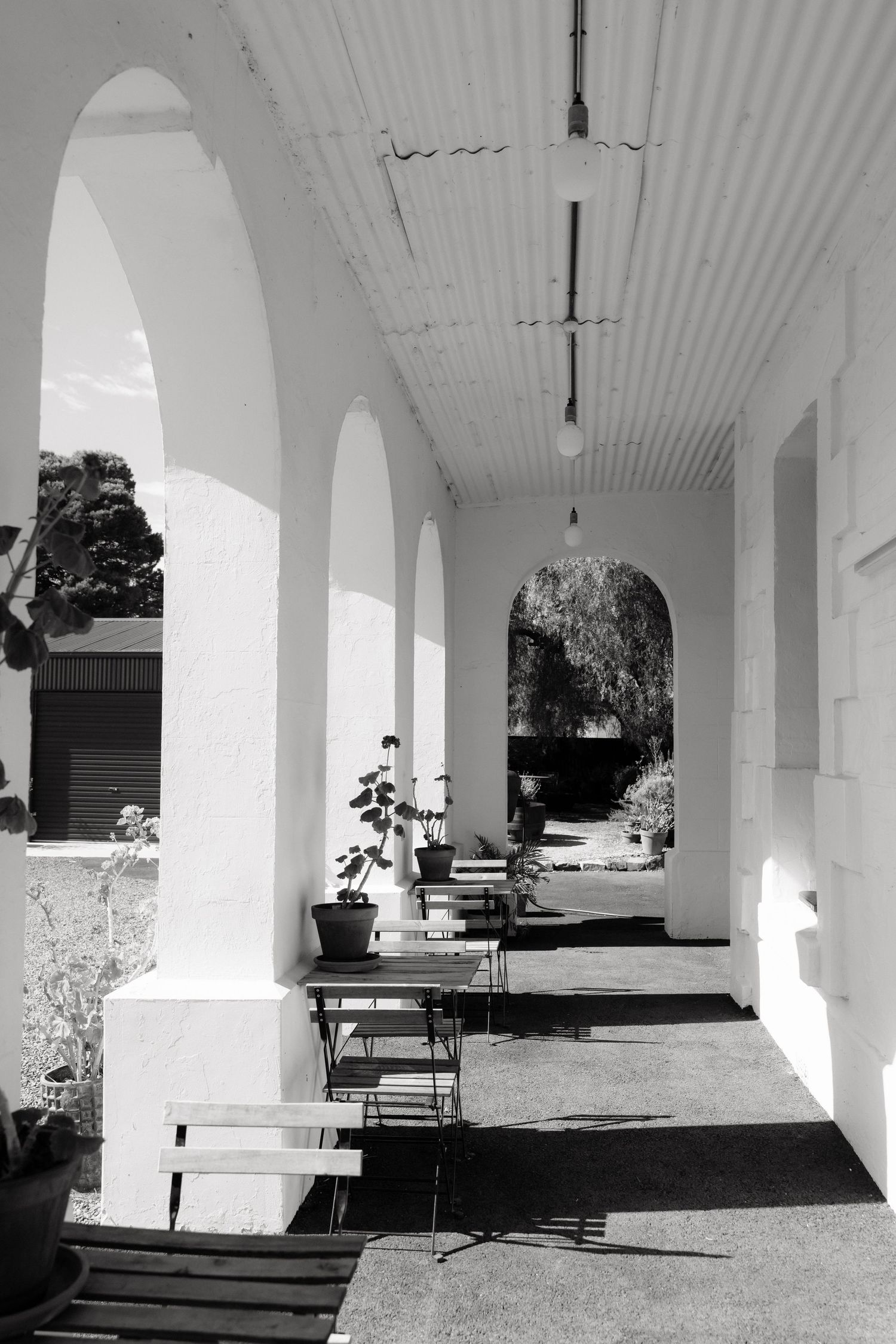 Black and white photo of elegant arched veranda with bistro tables at historic wedding venue.