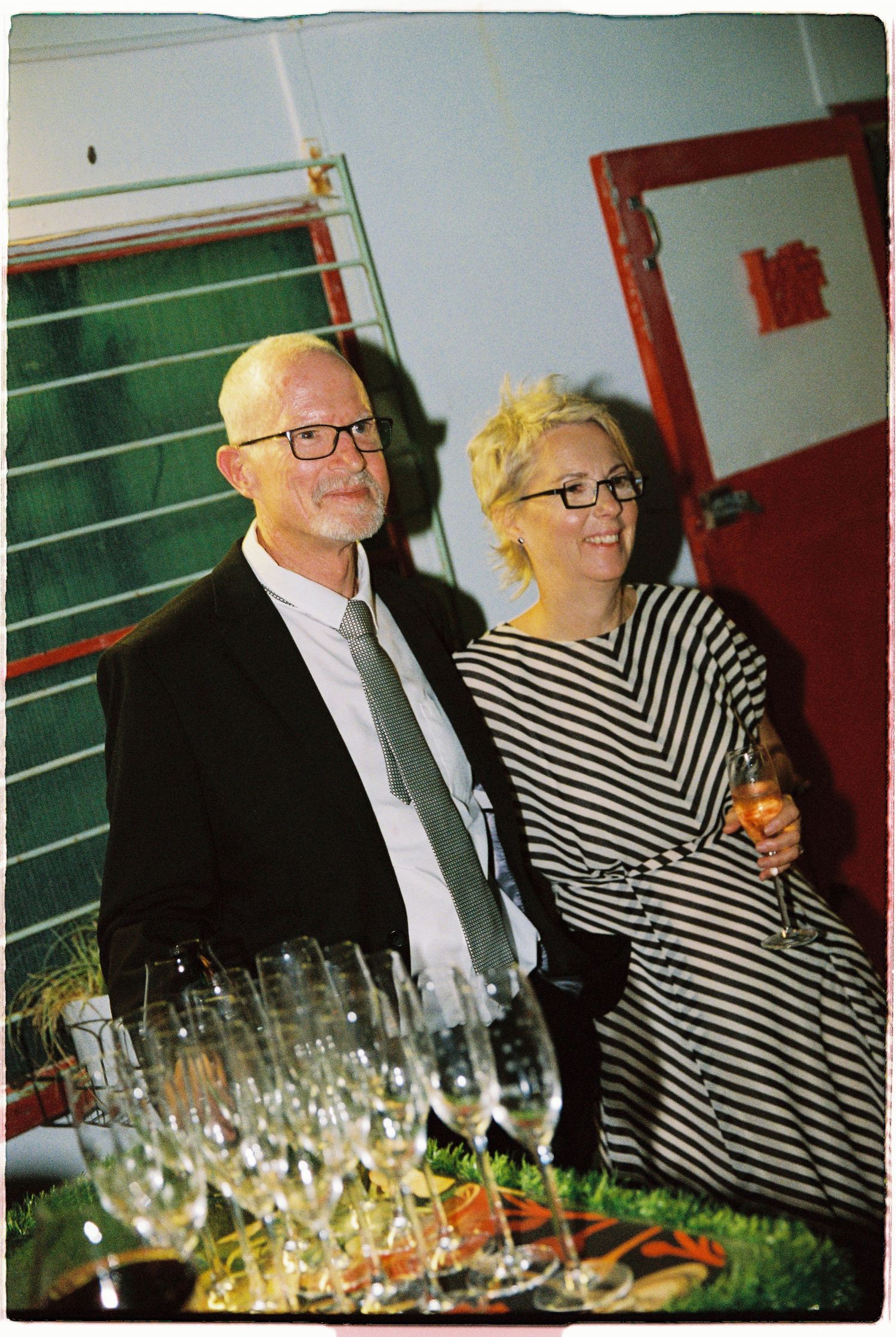 Elegant older couple in formal attire smile together at a wedding reception.