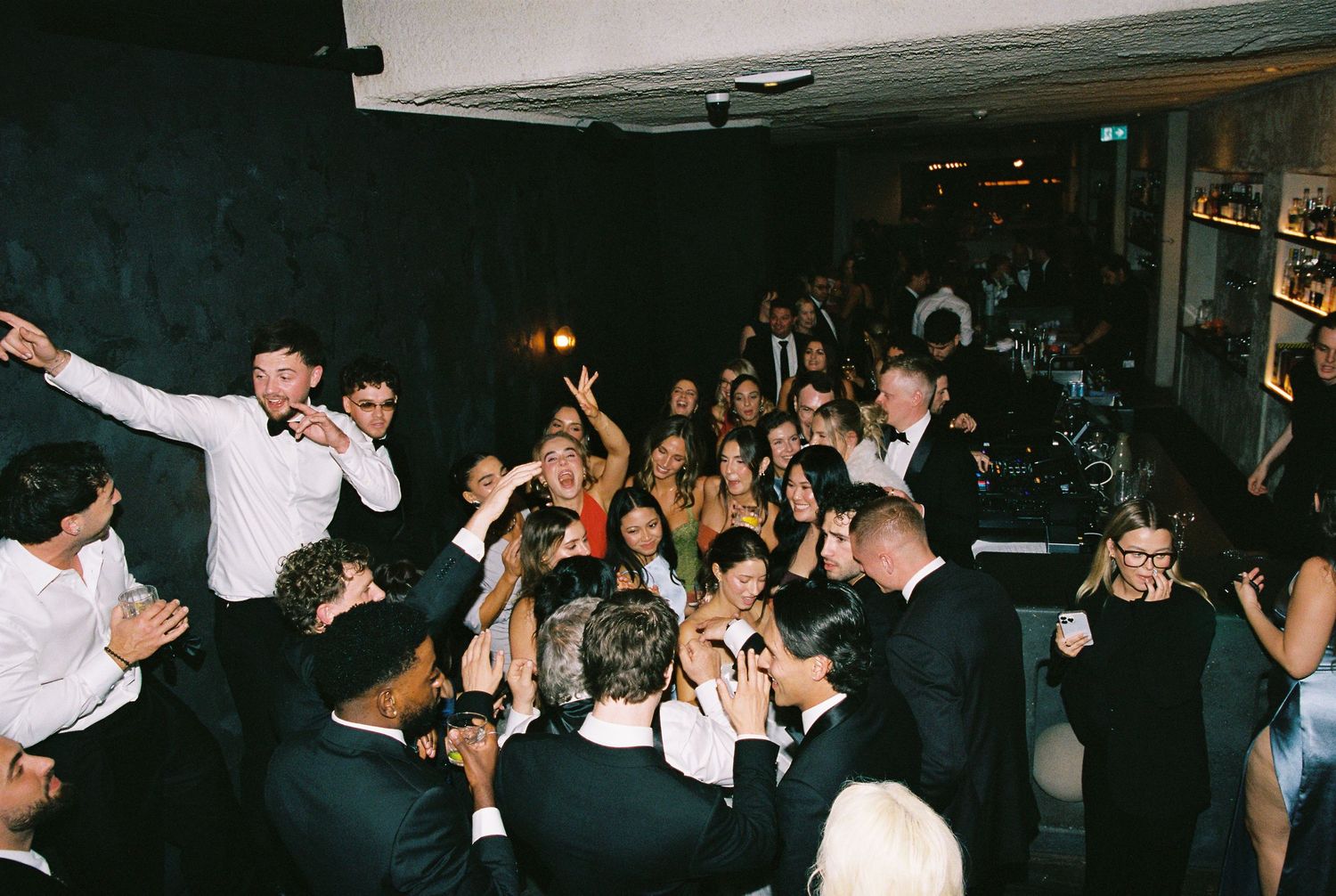 Energetic wedding guests celebrate on packed dance floor at lively reception party.