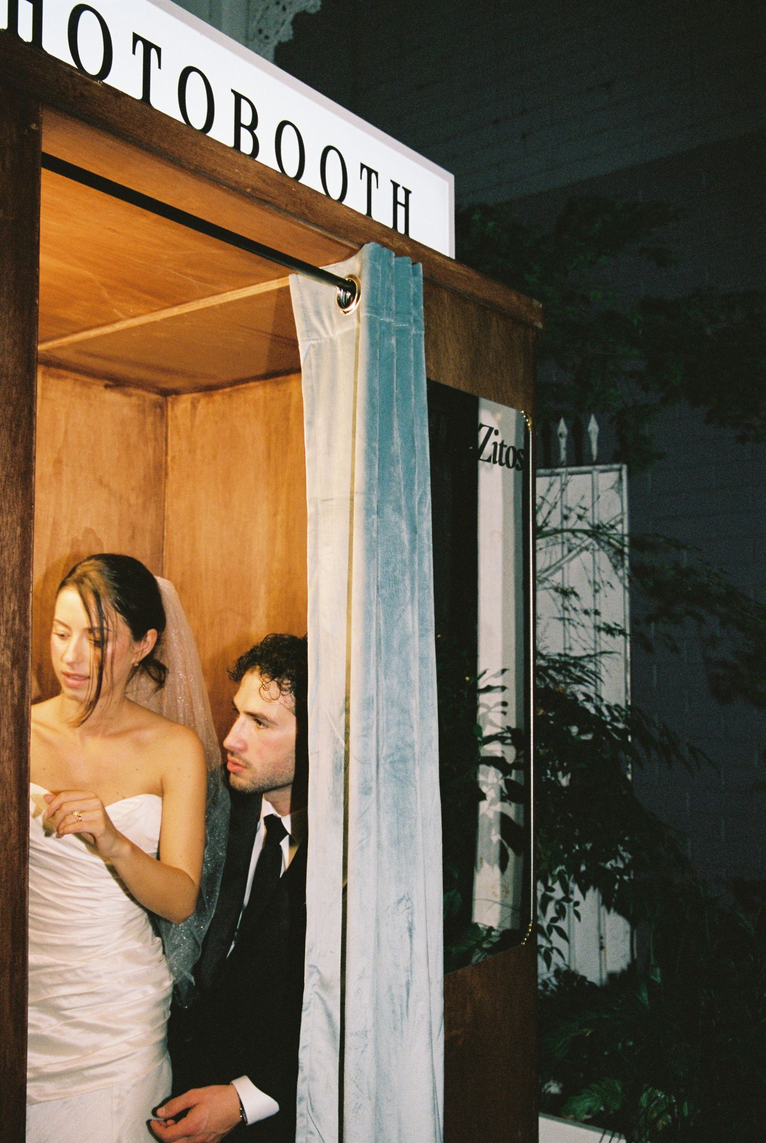 Bride and groom sharing a moment inside a vintage photo booth at their wedding reception.