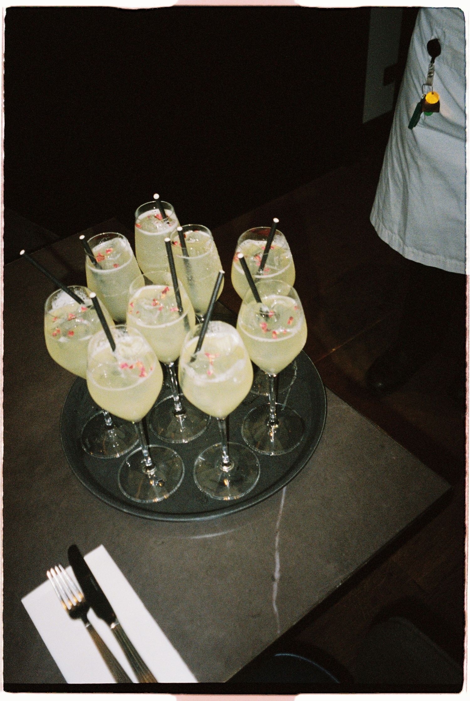 Tray of elegant champagne and cocktail glasses garnished with pink flowers served at wedding reception.