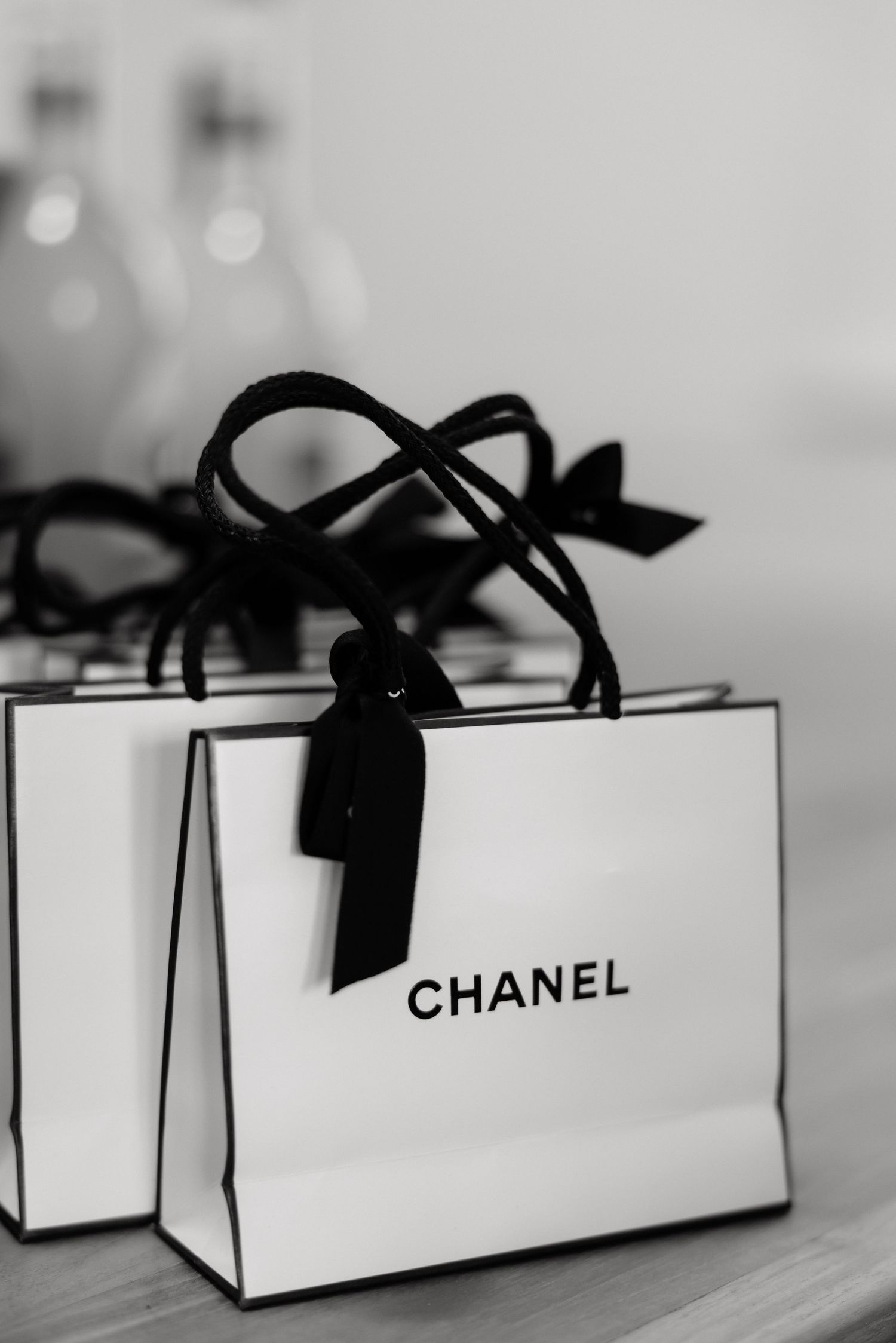 Luxury Chanel shopping bags with black ribbon bows, black and white bridal preparation photo.